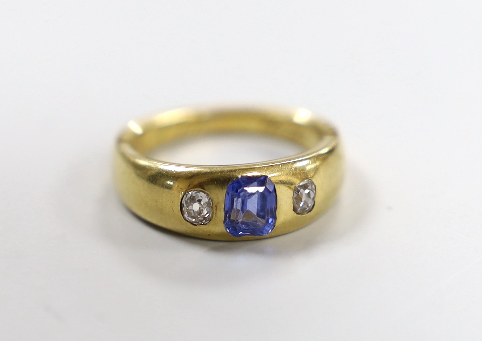 An 18ct and gypsy set single stone sapphire and two stone diamond ring, with interior engraved inscription (shank re-sized), size M, gross weight 6.5 grams.                                                                