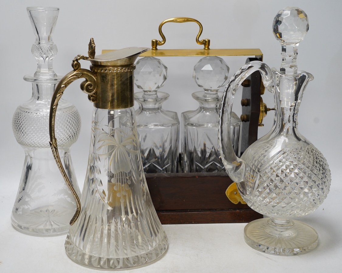 A brass mounted two bottle tantalus and three glass decanters / jugs, largest 32cm high. Condition - fair                                                                                                                   