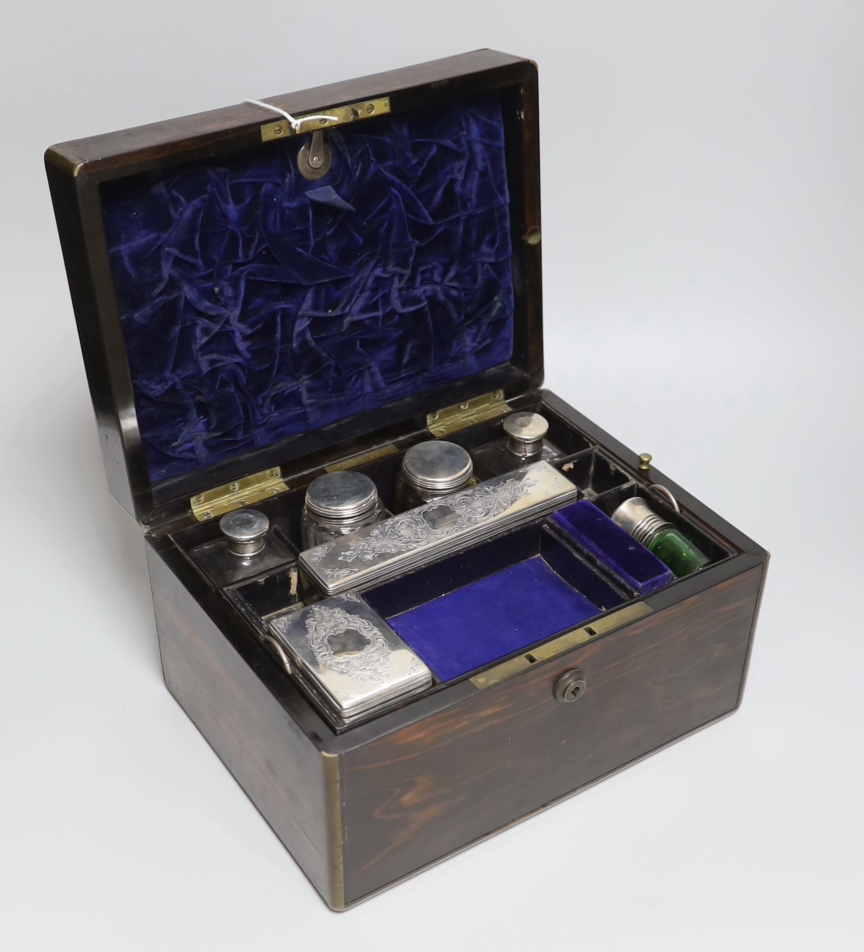 A Victorian brass mounted coromandel wood toilet box, retailed by C. Asprey, 166 Bond Street, containing six silver mounted glass toilet jars, London 1853, box width 28cm.                                                 