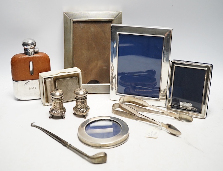 A collection of white metal and hallmarked silver to include three photo frames, a mounted glass flask, a compact, a lipstick holder, a cased pair of Victorian pepper pots, two pairs of Georgian sugar tongs and a mounted