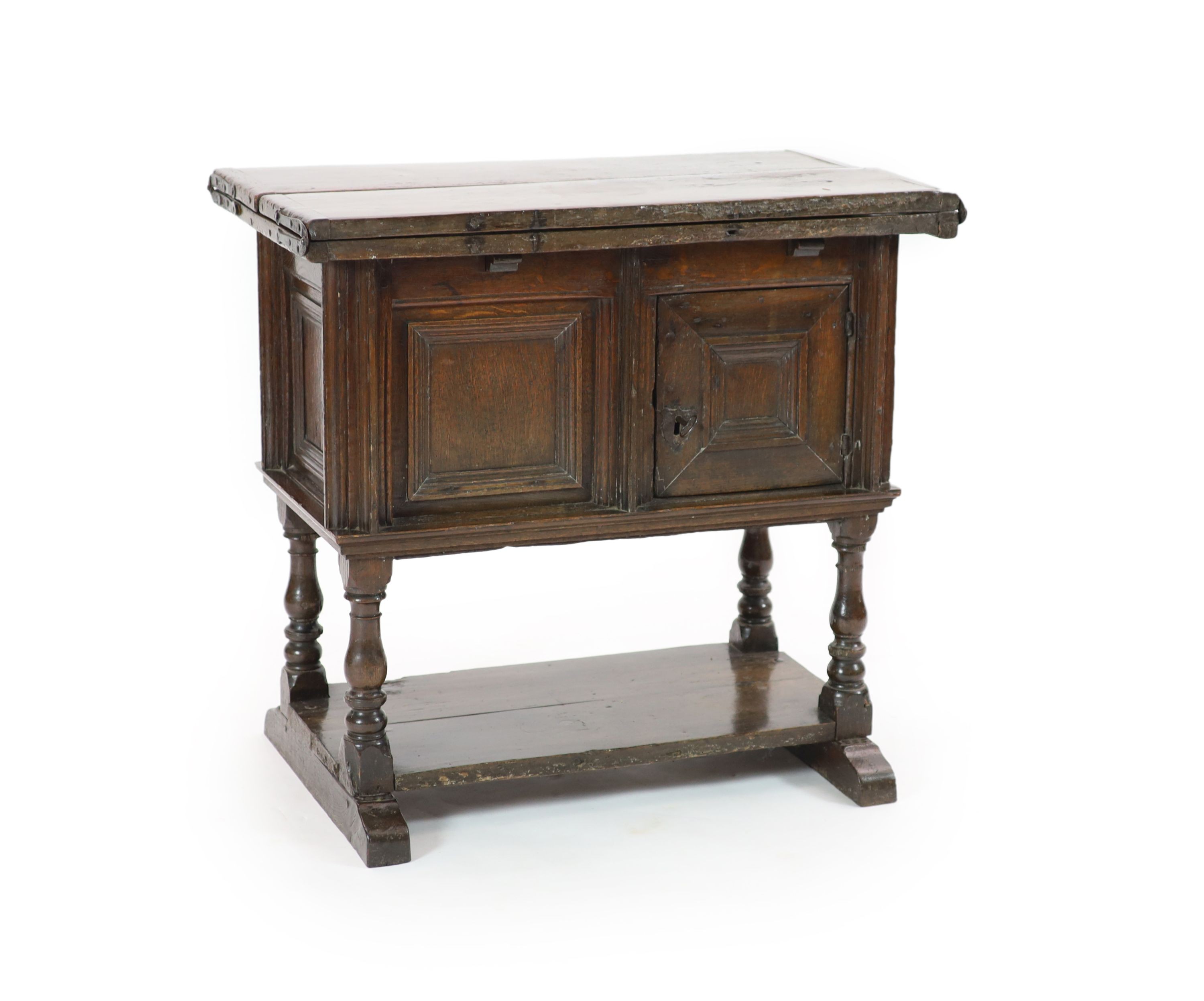 A 17th century rectangular oak drop-flap games table, fitted cupboard and undertier H 79cm. W 83cm. D 47cm.                                                                                                                 