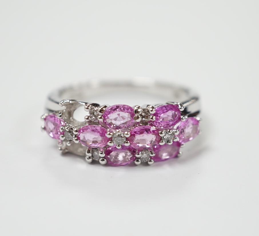 A modern 14k white metal, pink sapphire and diamond cluster set half hoop ring (two sapphires loose), size O, gross weight 4.7 grams.                                                                                       