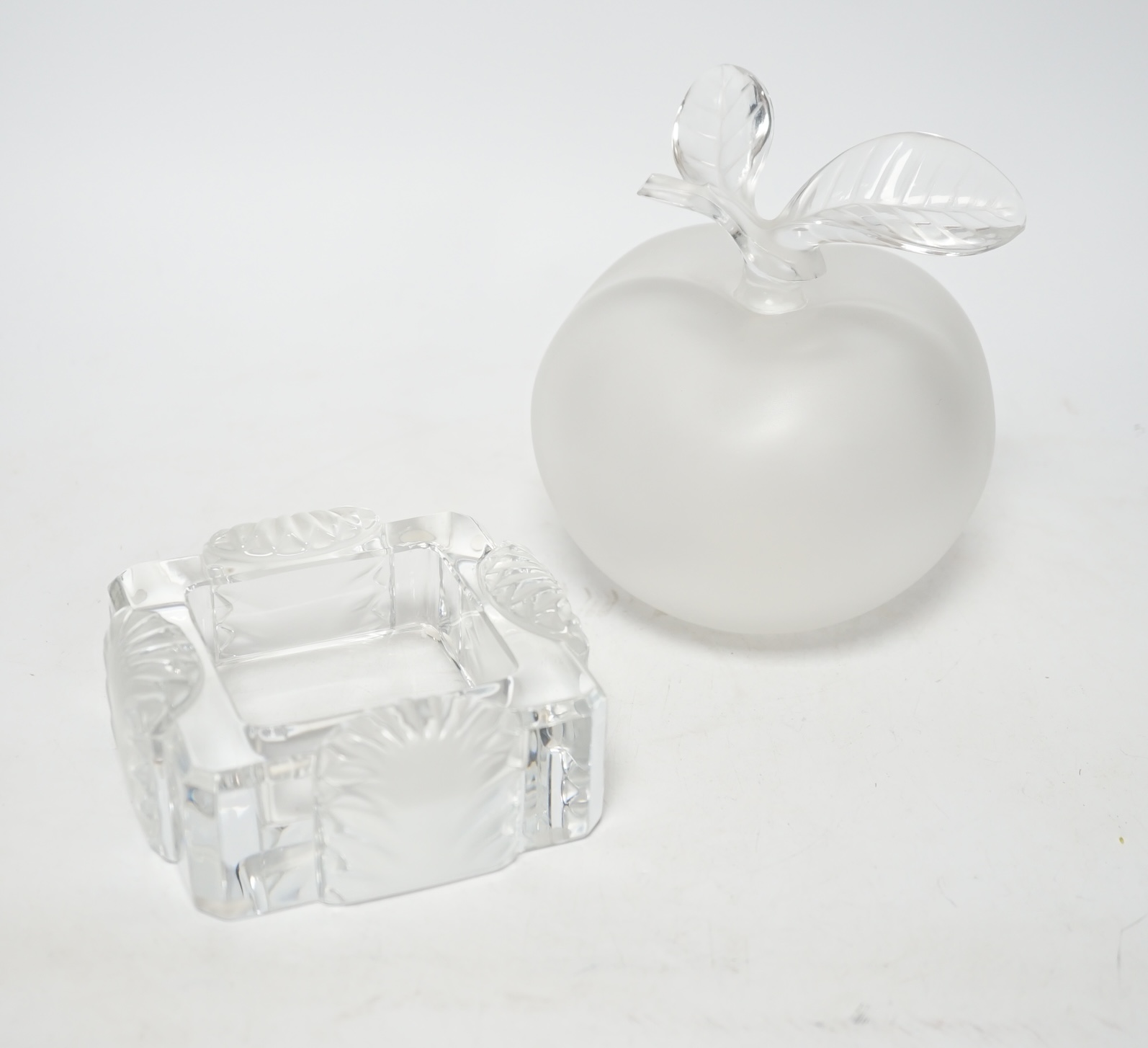 A Lalique apple shaped perfume bottle and leaf stopper together with a square ashtray, both with signed engraving to base, perfume bottle 14cm high                                                                         