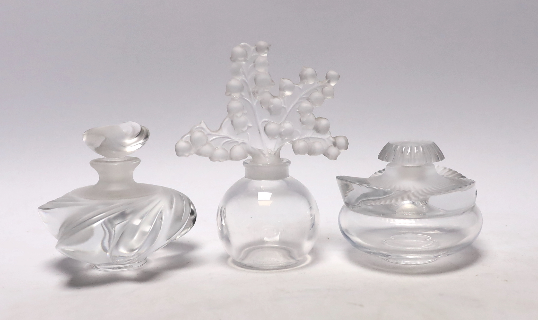 Three Lalique glass scent bottles and stoppers, one with Lily of the Valley stopper, 12cm                                                                                                                                   