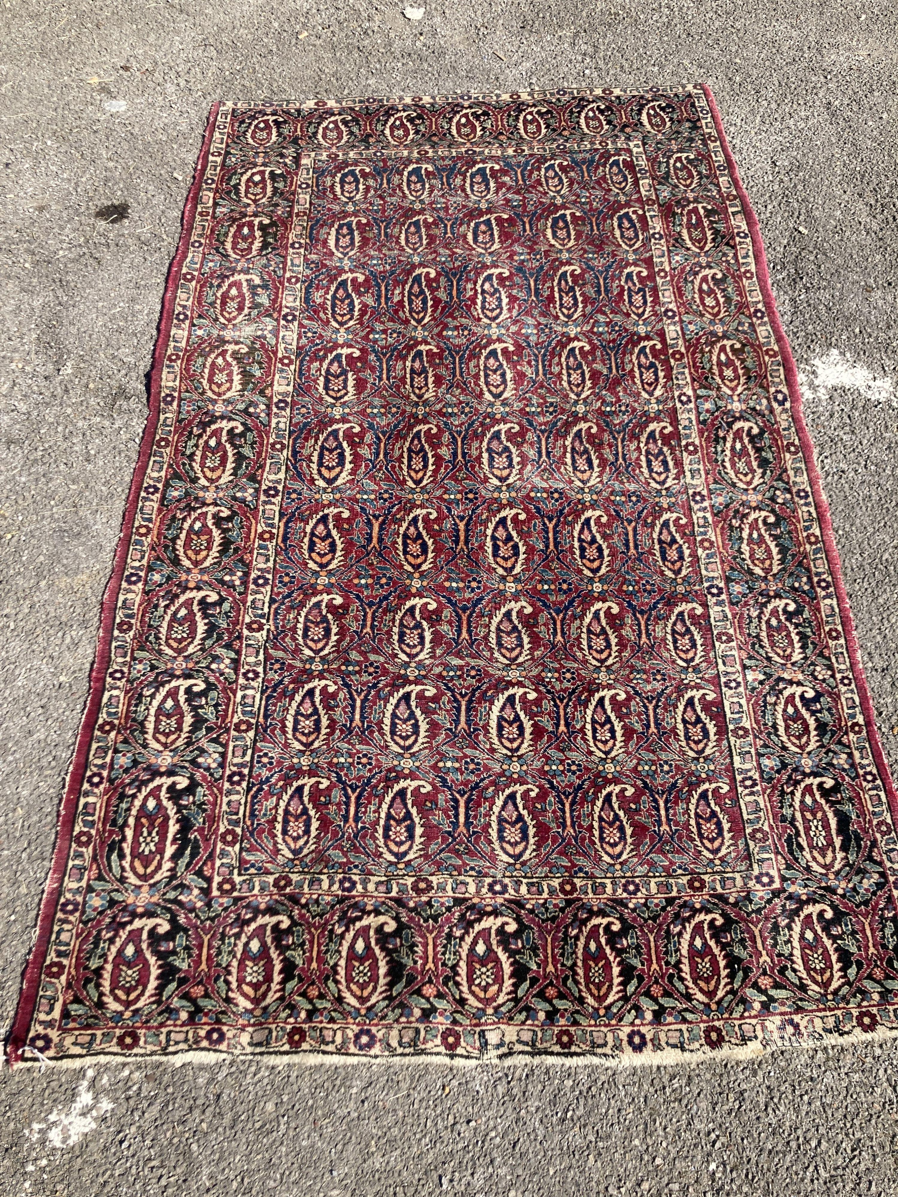 An early 20th century Persian Senneh red ground rug woven with rows of Boteh 218 x 130 cms                                                                                                                                  