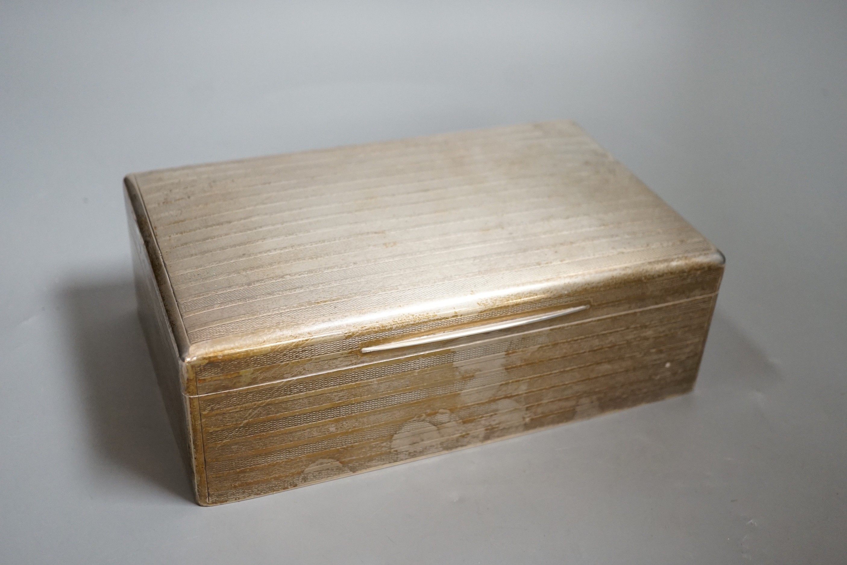 A George V engine turned silver mounted rectangular cigar/cigarette box, with interior inscription, London, 1915, 22.3cm.                                                                                                   