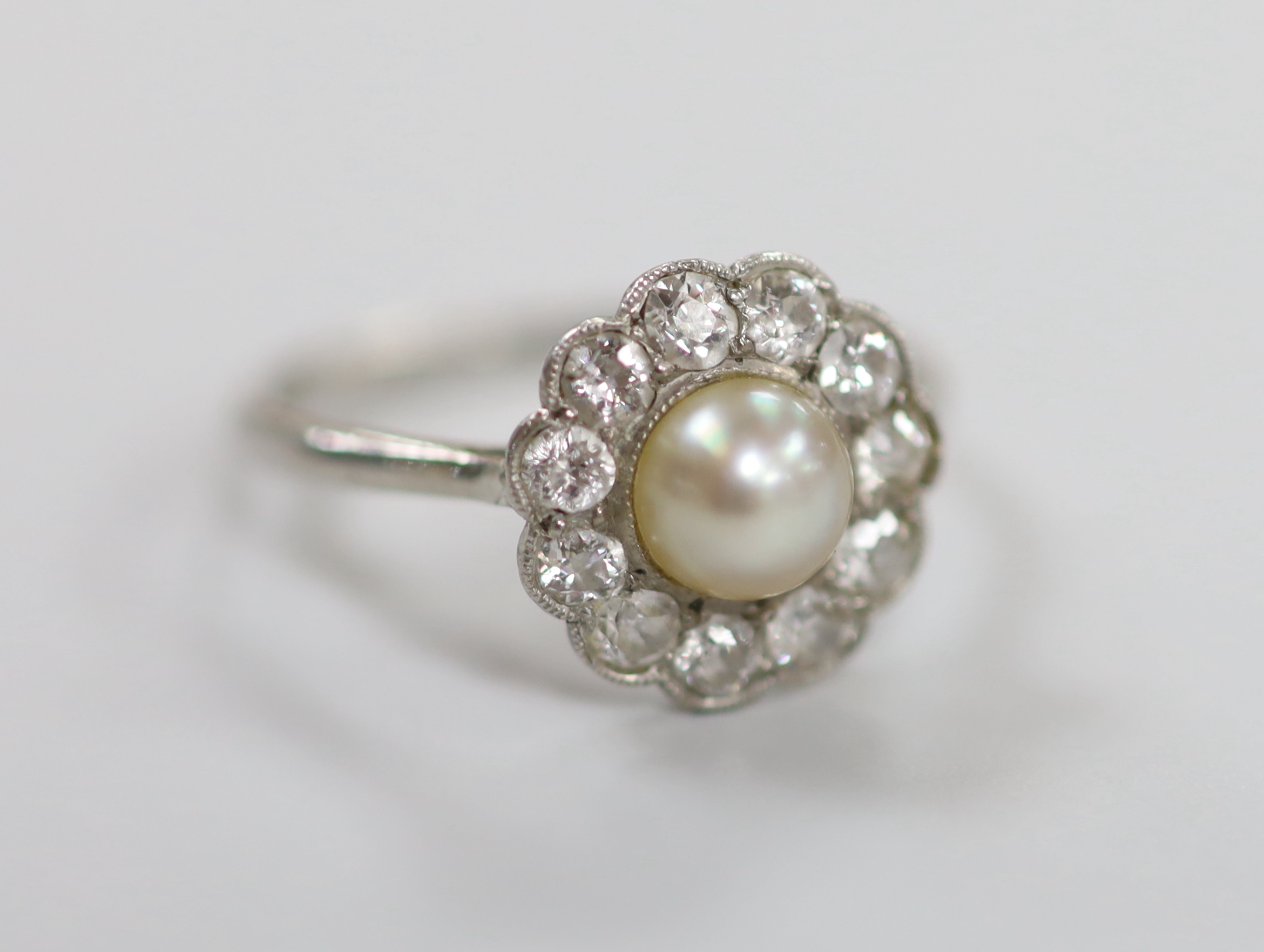 A 1920's white metal, cultured pearl and diamond set circular cluster ring, size M/N, gross weight 3.3 grams.                                                                                                               