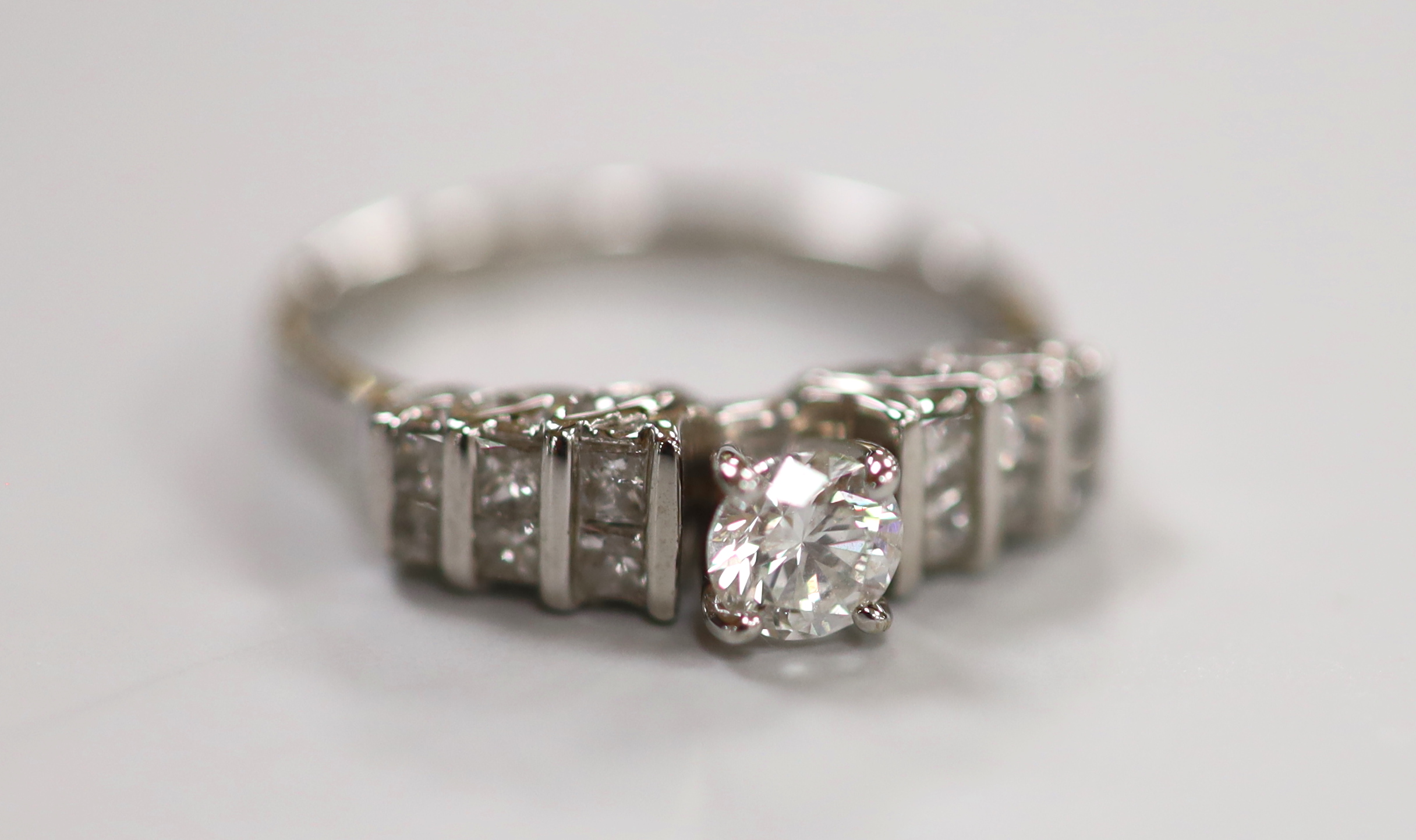 A modern 18ct white gold and single stone diamond ring, with three row graduated diamond set shoulders, size N, gross weight 4.2 grams.                                                                                     