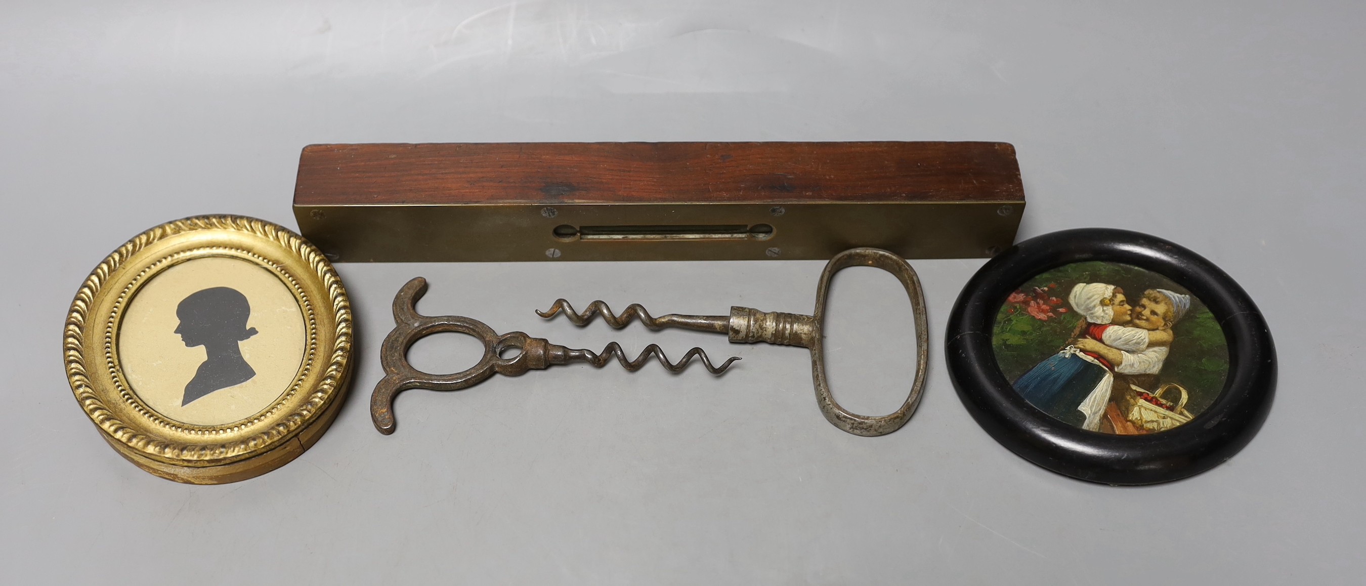 A George III framed silhouette, two corkscrews, spirit level and circular miniature painting                                                                                                                                