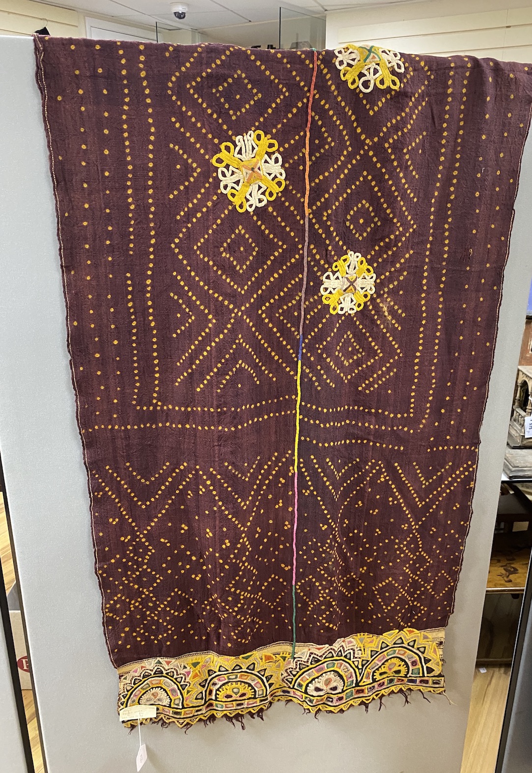 A late 19th century early 20th century hand woven, hand dyed, Indian wall hanging, woven in two narrow loom panels, joined and finished with ornate embroidered and mirrored end 86cm wide, 280cm long                      