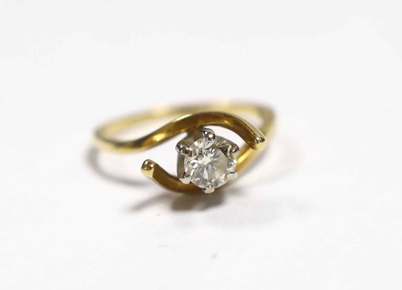 A yellow metal and solitaire diamond set ring, with crossover shoulders, size M, gross weight 3.5 grams.                                                                                                                    