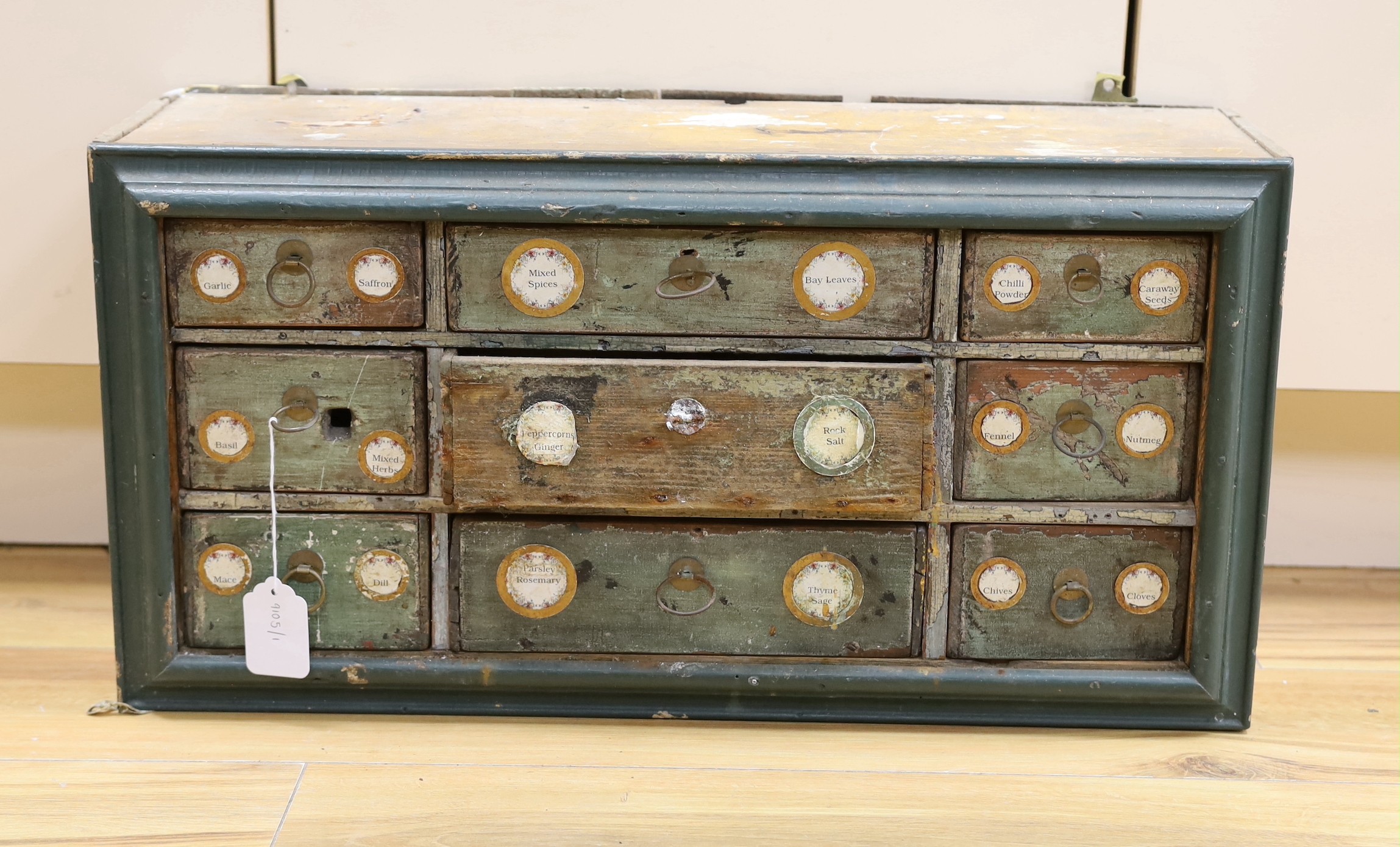 An early 20th century painted nine drawer spice hanging cupboard, 62cms wide, 31cms high                                                                                                                                    