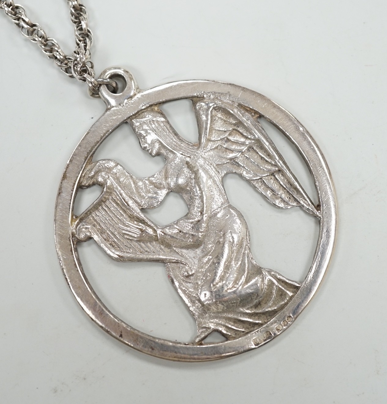 A late 1970's John Skelton silver pendant, depicting an angel with harp, diameter 63mm, on a sterling chain.                                                                                                                