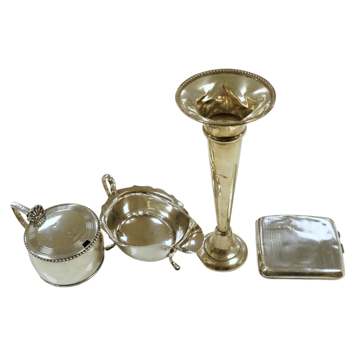 A George VI silver sauceboat, a George III drum mustard, a George V cigarette case and a loaded specimen vase, 10.5 oz of weighable silver. Condition - mustard lacks liner, vase dented, otherwise good                    