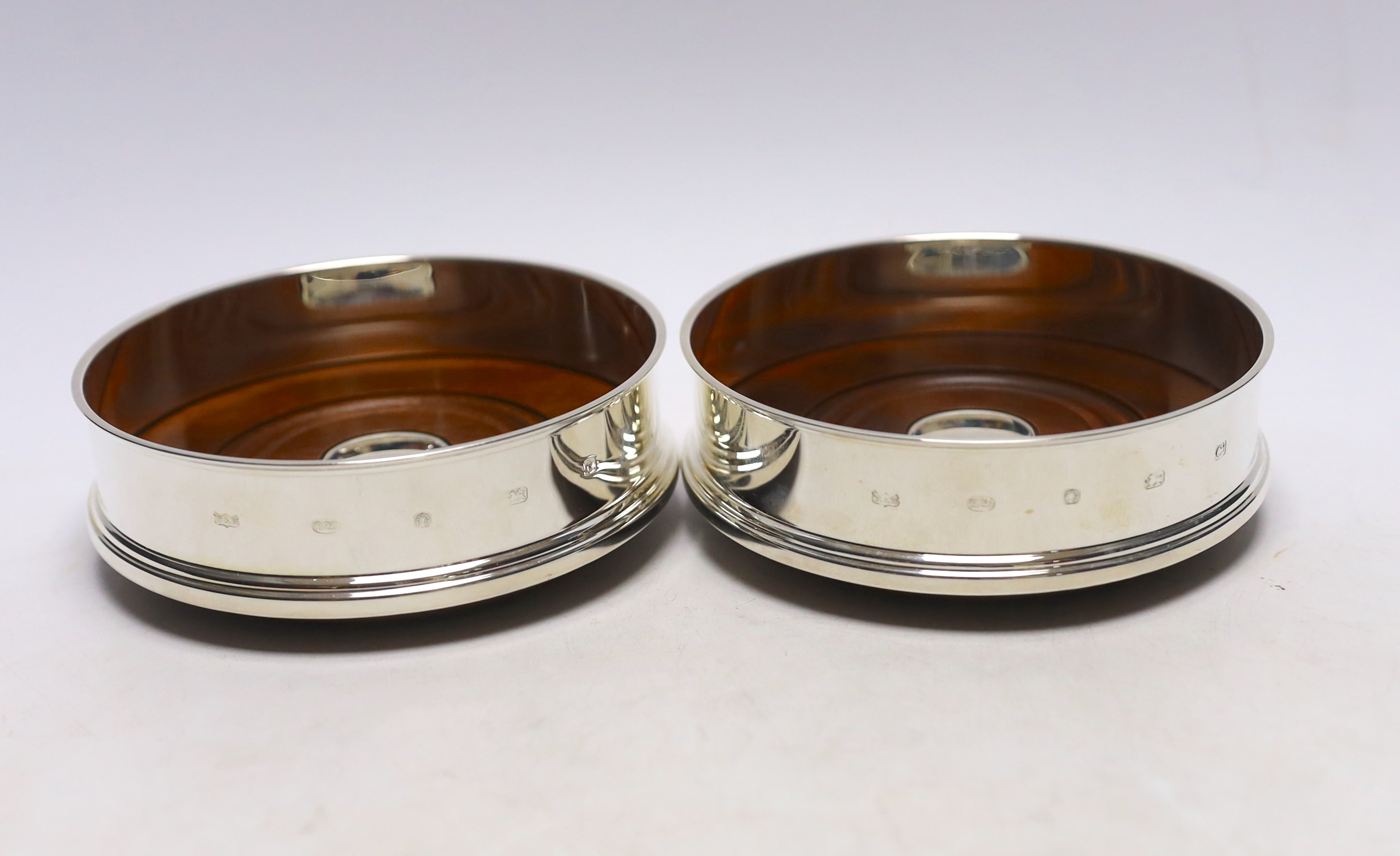 A pair of Elizabeth II silver mounted wine coasters, with turned wooden bases, Roberts & Dore, Sheffield, 2002, diameter 12.4cm, each individually boxed.                                                                   