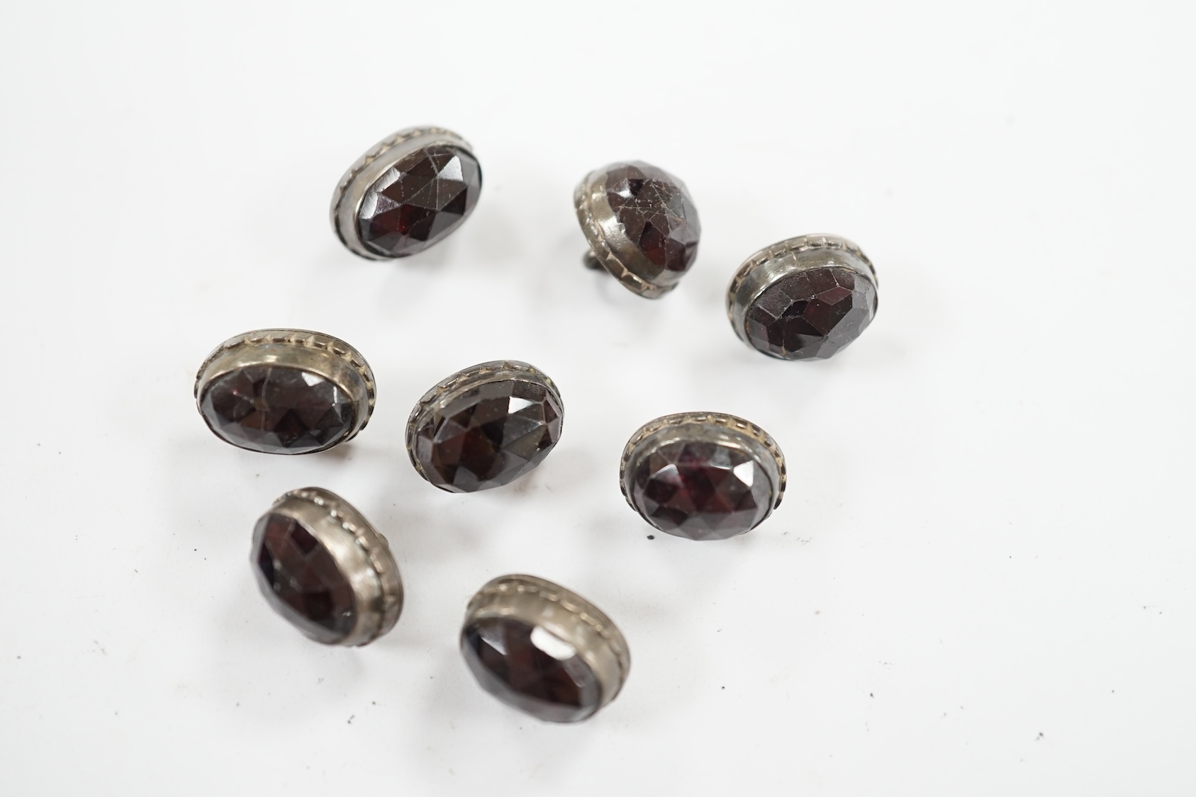 A set of eight 19th century white metal and facetted garnet set buttons, 12mm. Condition - fair but wear to the stones                                                                                                      