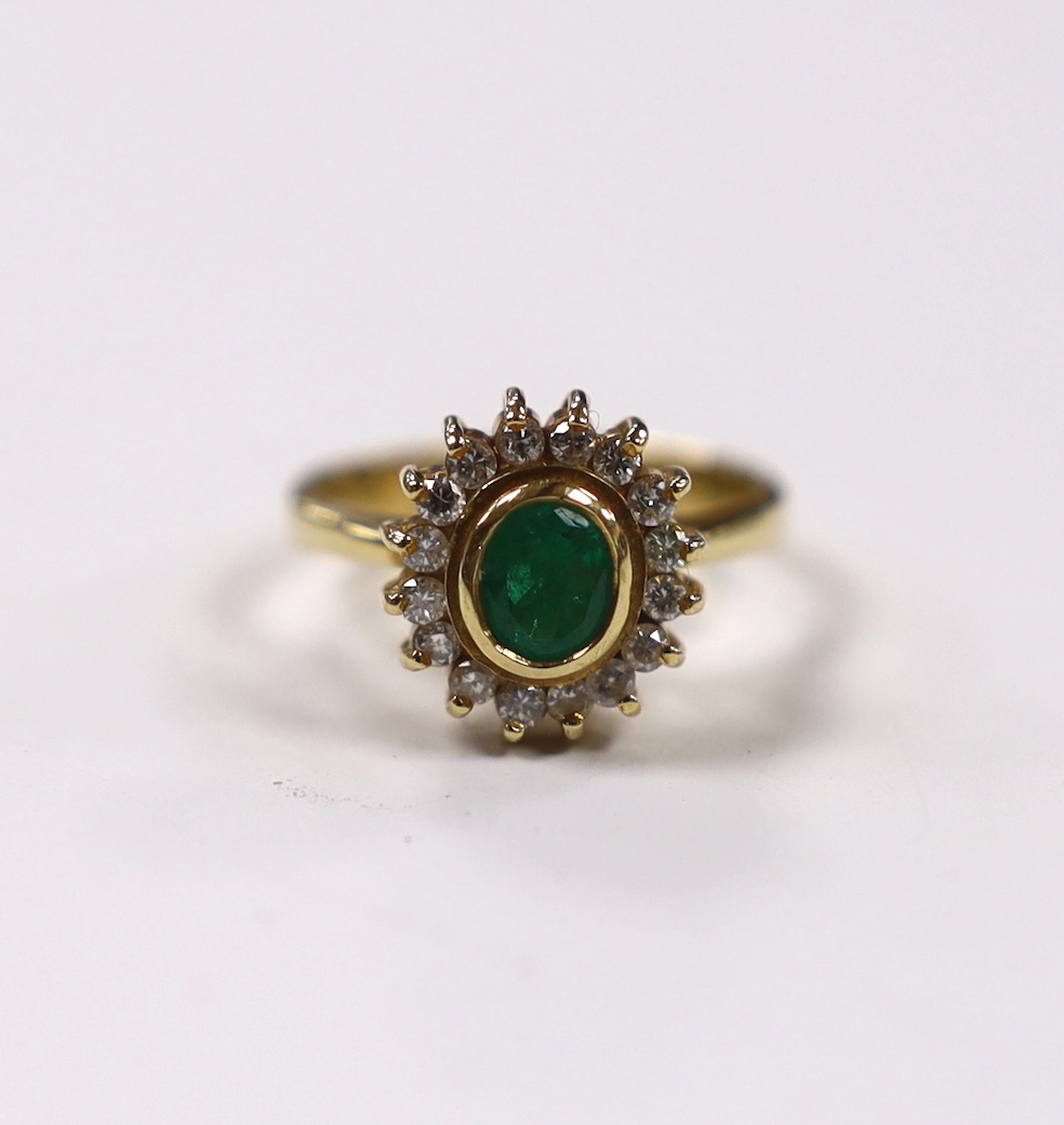 An 18k, emerald and diamond set oval cluster ring, size L, gross weight 5 grams.                                                                                                                                            