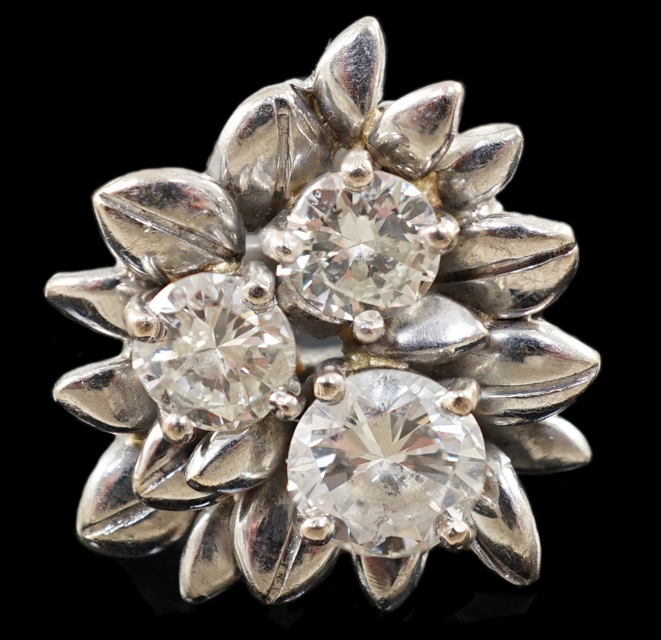 An 18ct white gold and three stone diamond set flowerhead ring                                                                                                                                                              