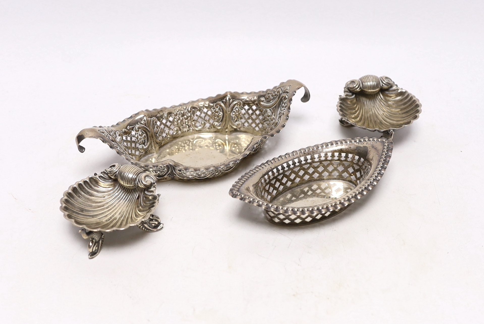 A pair of Victorian silver shell salts, on dolphin supports, London, 1876, 69mm and a two pierced silver bonbon dishes.                                                                                                     