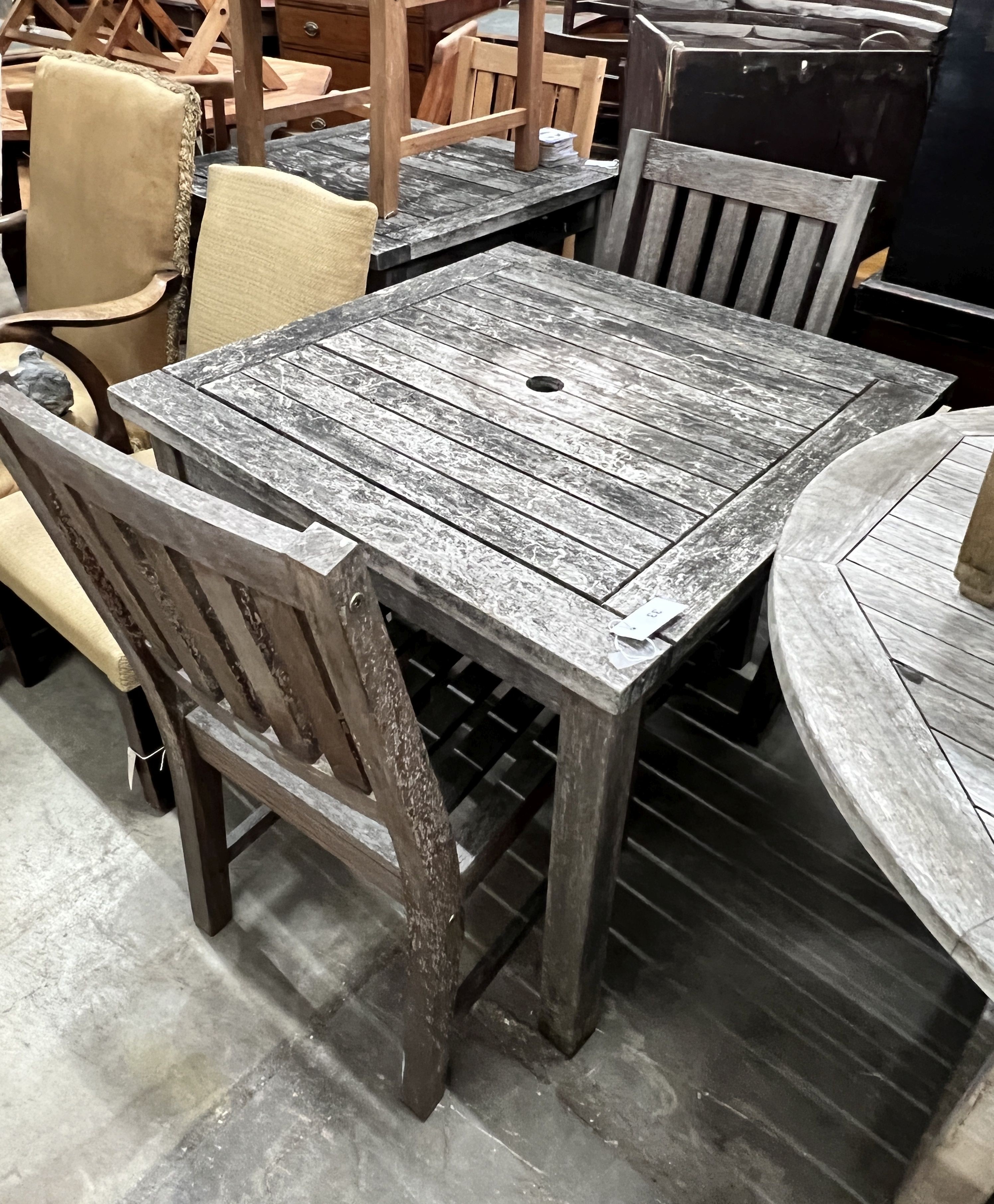 A square weathered teak garden table, width 80cm, height 73cm together with two teak garden chairs                                                                                                                          