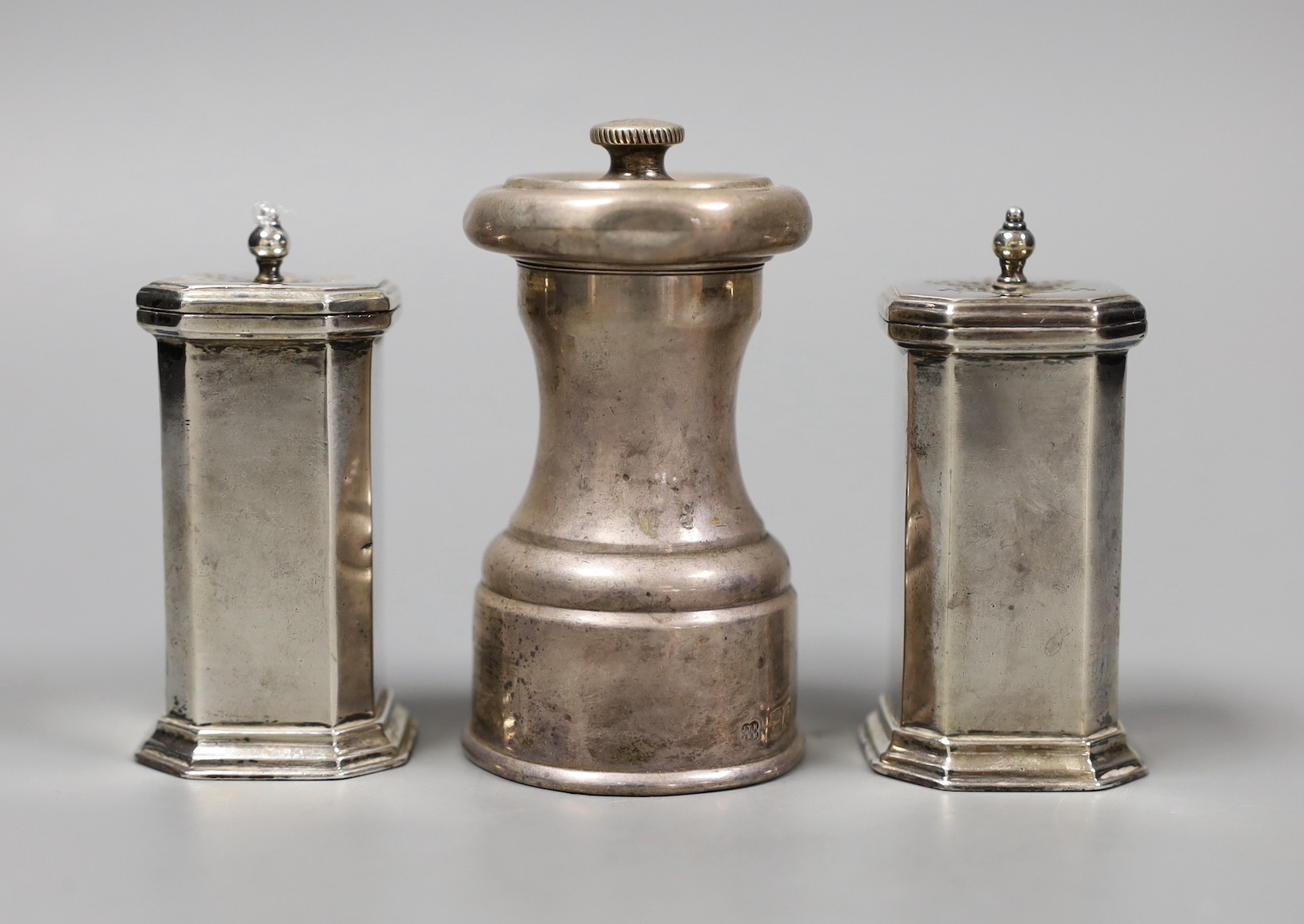 A pair of George V silver pepperettes, Birmingham, 1922, 72mm and a late Victorian silver pepper mill, Hukin & Heath, London, 1896.                                                                                         
