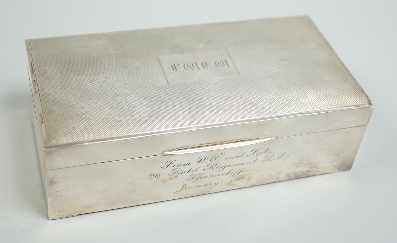 A Elizabeth II engine turned silver mounted rectangular cigarette box, 17.8cm, with engraved inscription, Birmingham, 1952.                                                                                                 