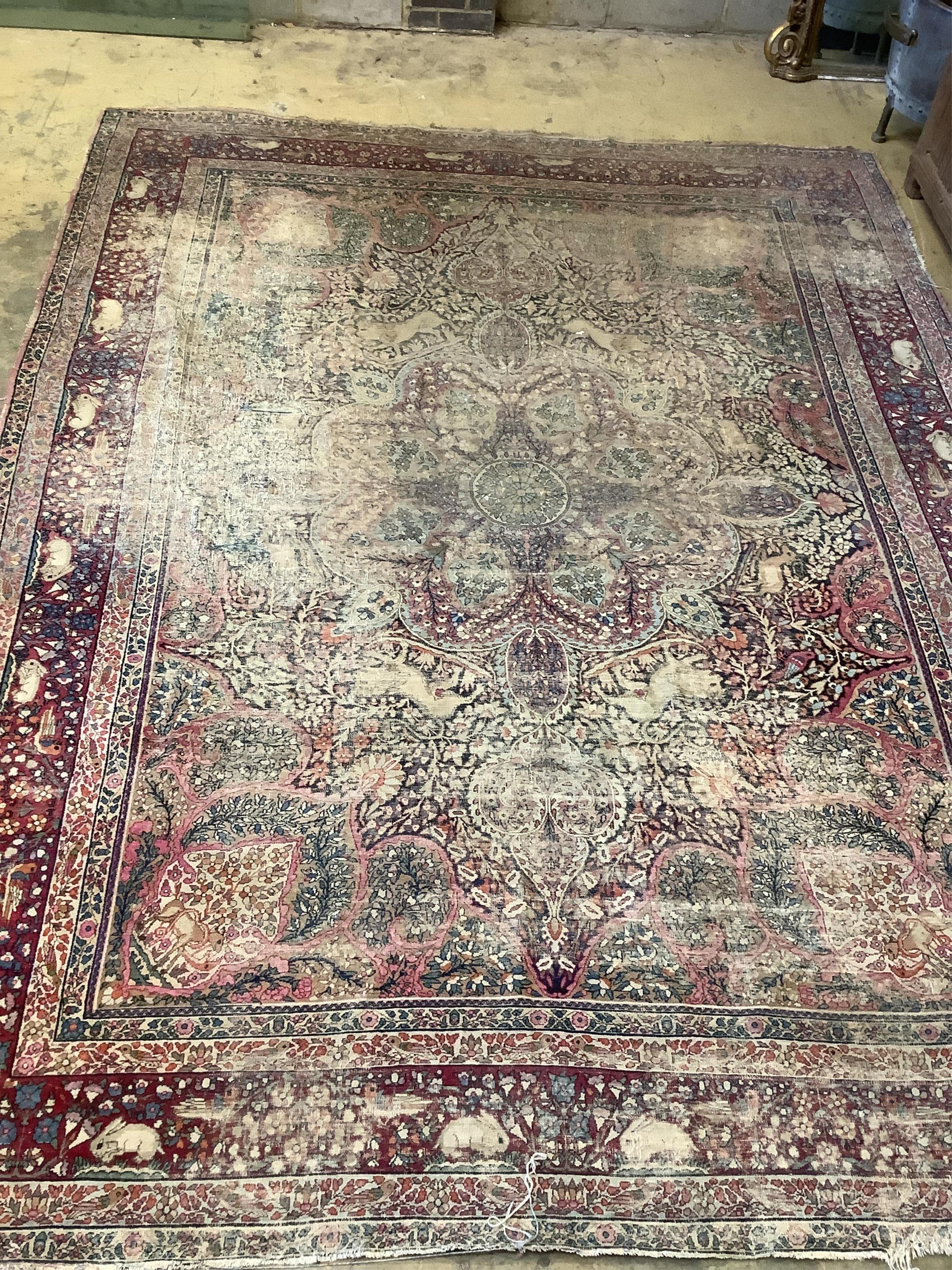 An antique Kirman ivory ground pictorial carpet (severely worn), 348 x 265cm                                                                                                                                                