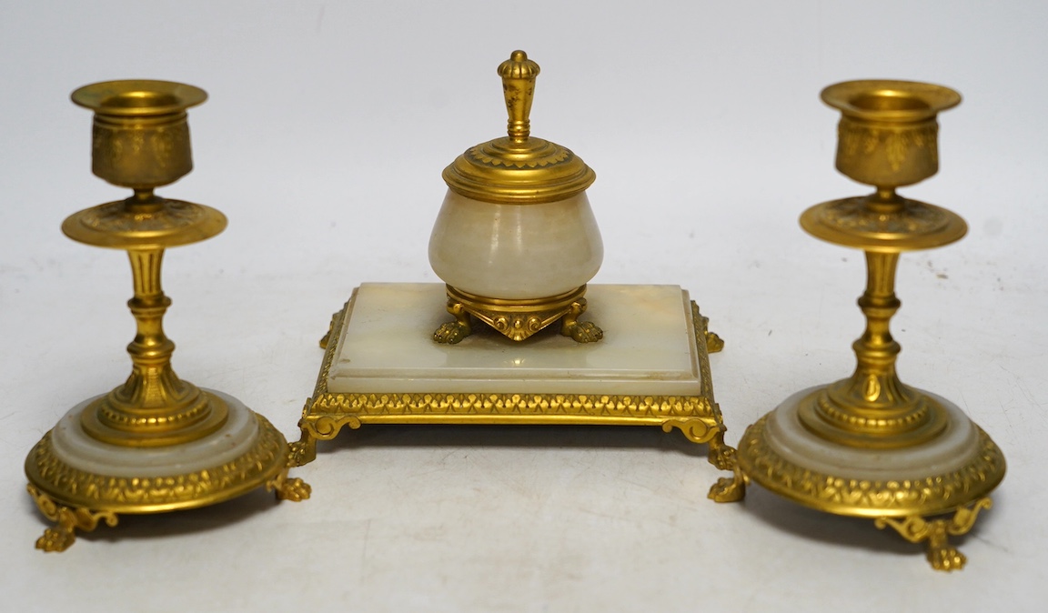 An early 20th century onyx and gilt metal desk set comprising inkwell and a pair of candlesticks, 13.5cm. Condition - fair to good                                                                                          