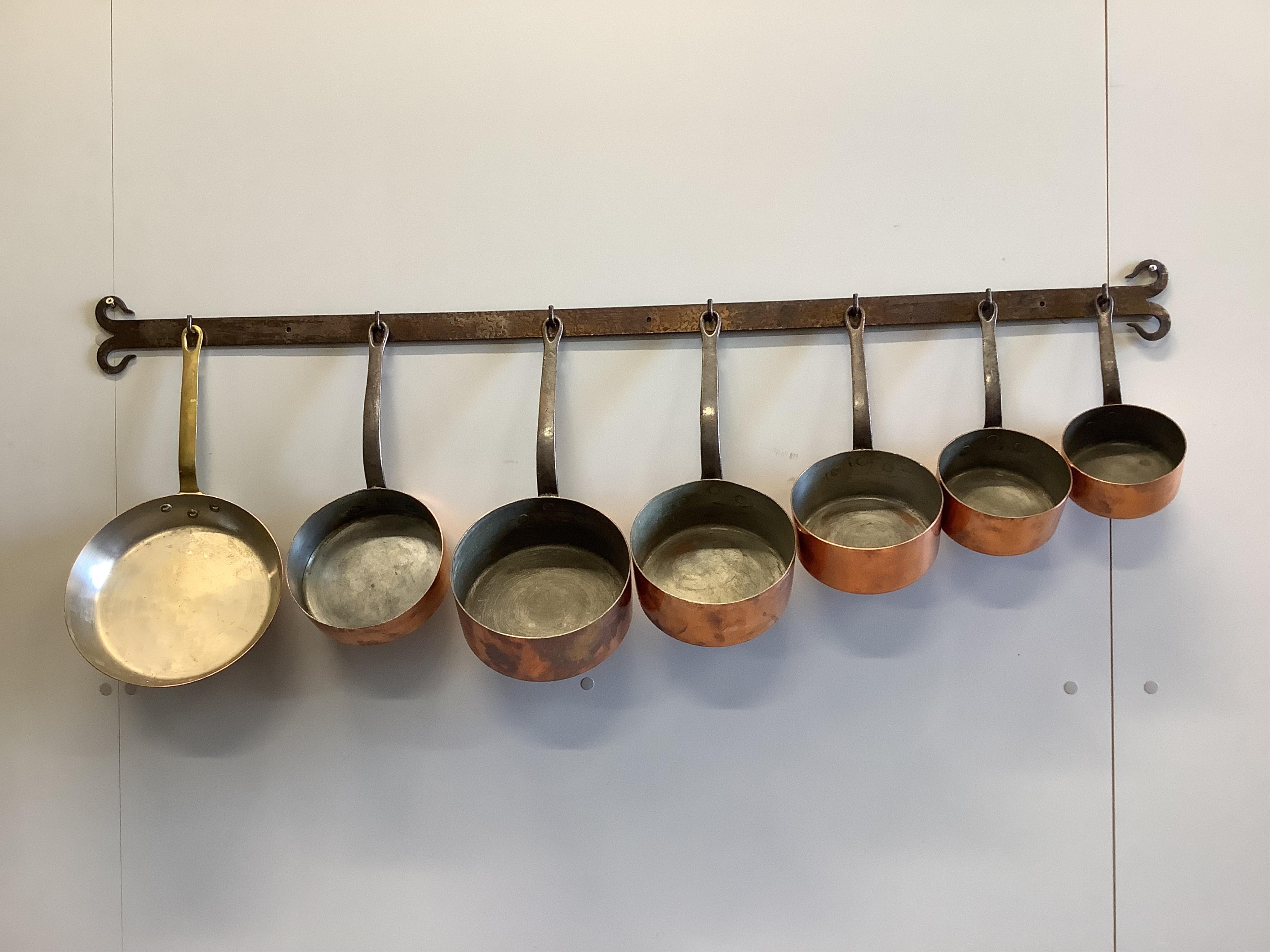 A graduated set of five French copper and wrought iron saucepans together with two further pans, larger diameter 24cm with wrought iron hanging rack, length 130cm. Condition - fair                                        