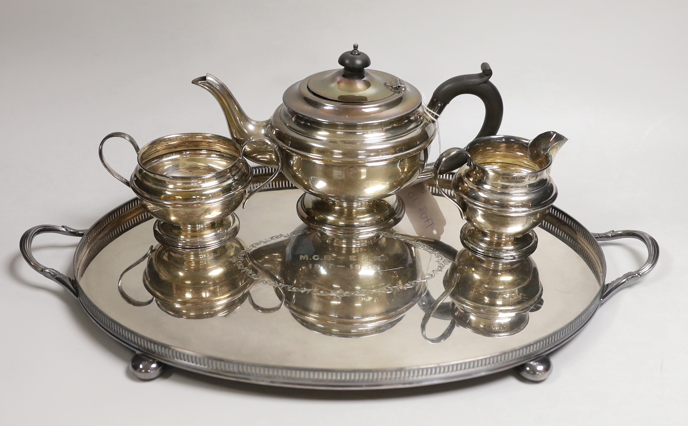 A George VI silver three-piece tea set, with engraved inscription, W.F. Mitchell, Birmingham, 1936, gross weight 22oz and a plated two handled tea tray, 49.3cm.                                                            