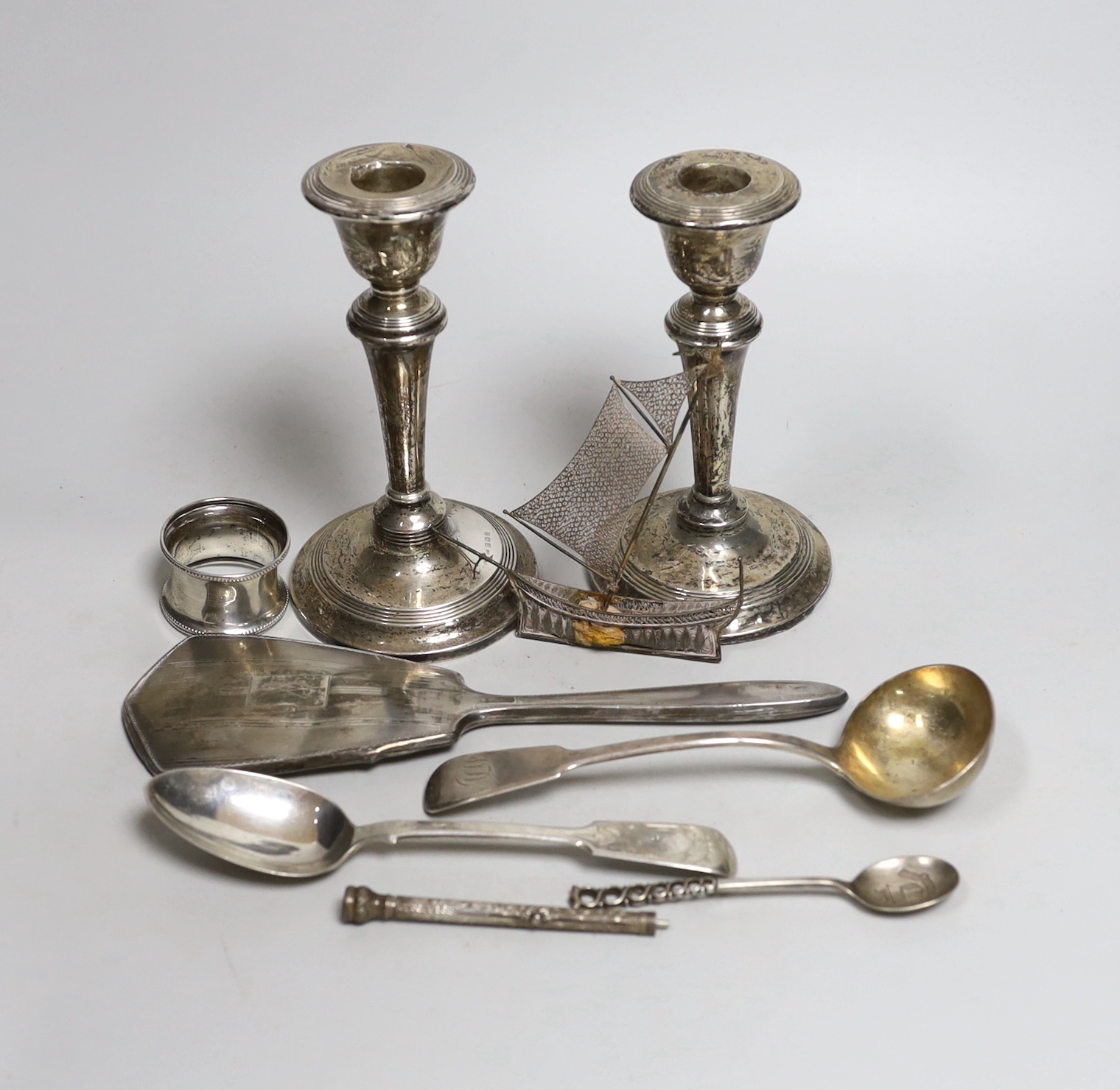 A pair of Edwardian silver candlesticks, Birmingham, 1909, 15.2cm (a.f.) a George IV silver sauce ladle and other items including a napkin ring and two silver spoons.                                                      