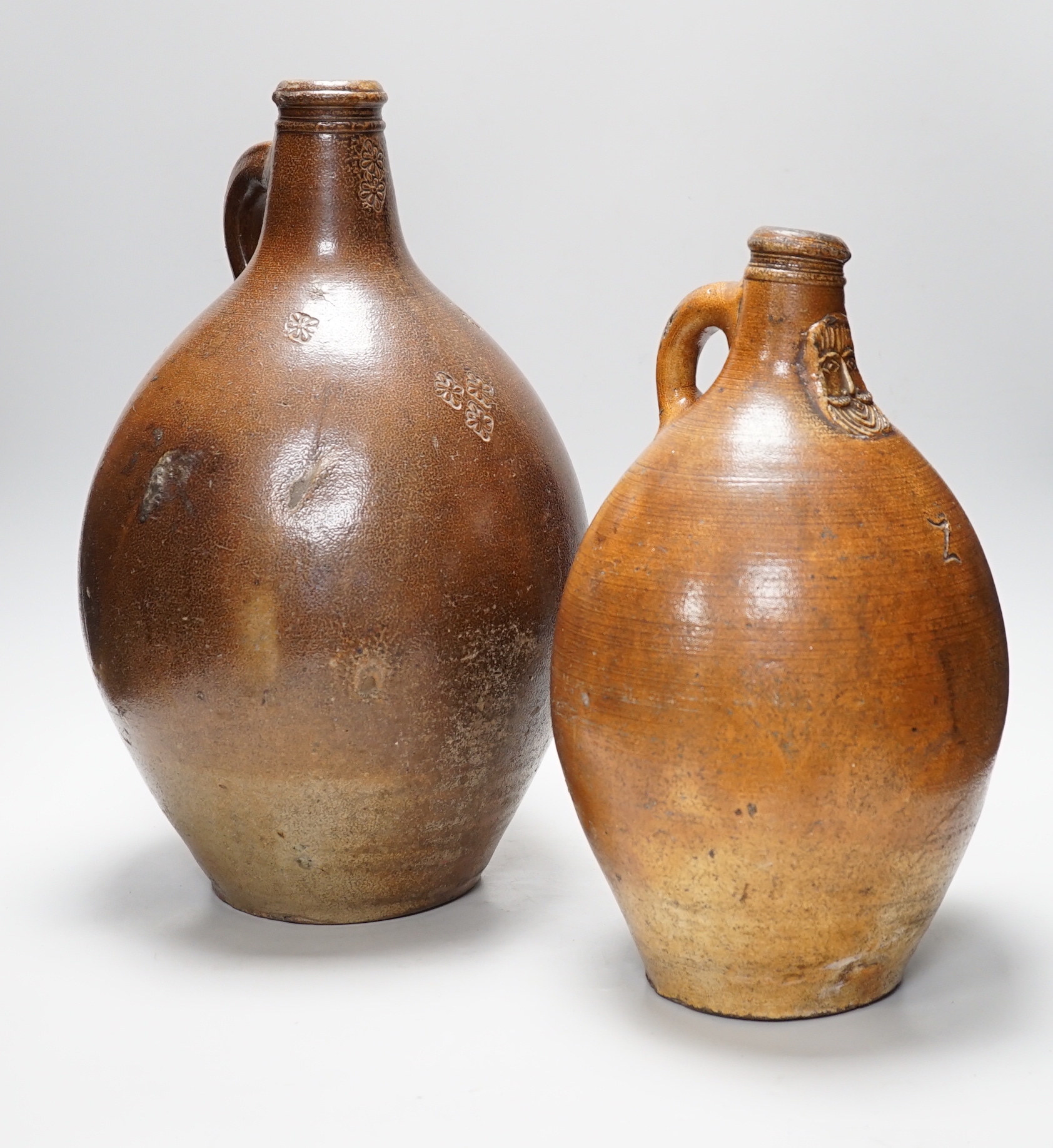 A large 17th century stoneware Bellarmine, incised Z, 42cm high and a large 18th century stoneware jug, 34cm high                                                                                                           