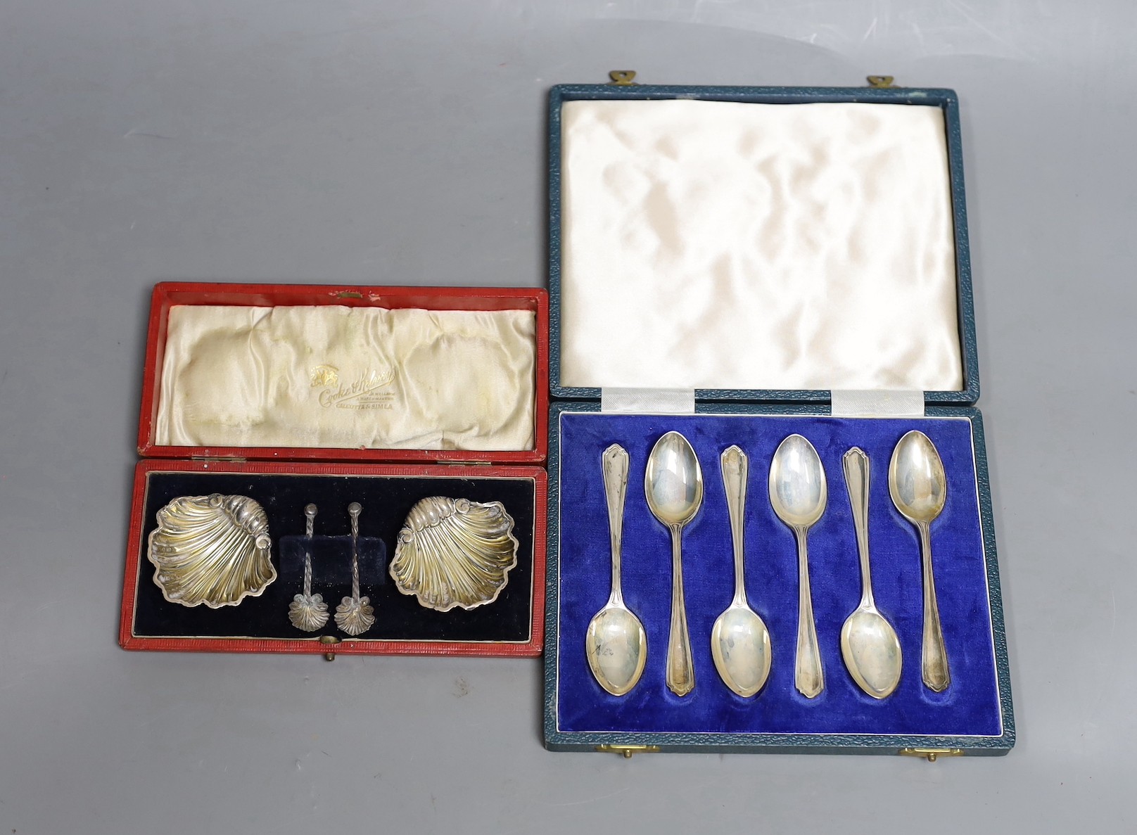 A cased pair of Edwardian silver shell salts and matching spoons, Birmingham, 1903, 51mm and a cased set of six modern silver teaspoons.                                                                                    