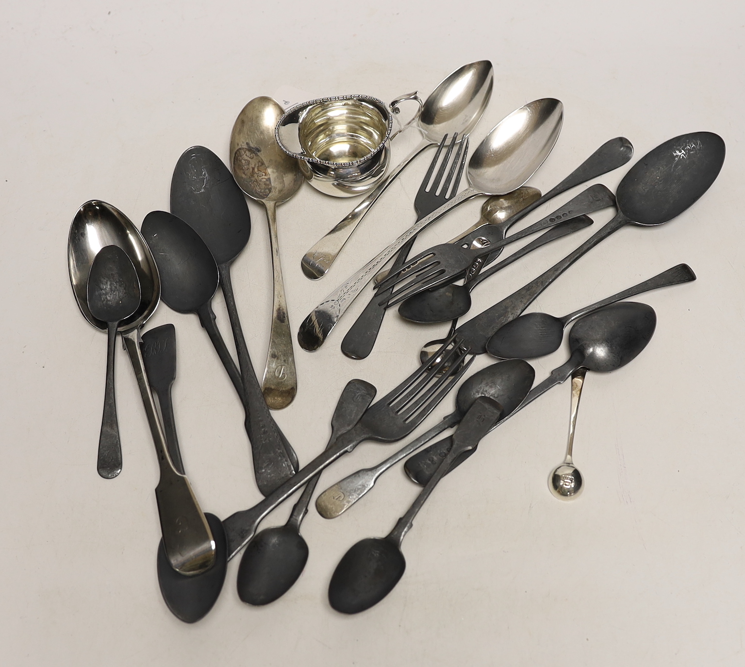 Twenty two assorted items of mainly 19th century flatware, various patterns, dates and makers, together with a small silver cream jug, 25.4oz.                                                                              