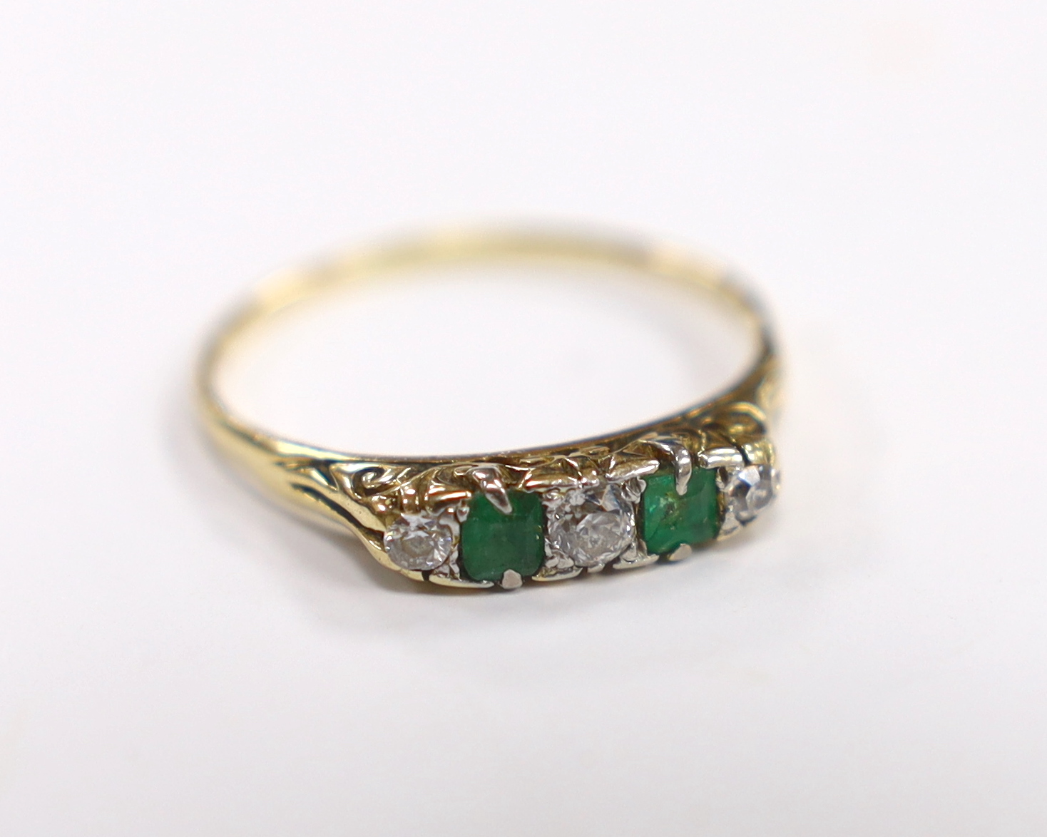 An 18ct, two stone emerald and three stone diamond set half hoop ring, size U, gross weight 2.8 grams, in a book shaped box.                                                                                                