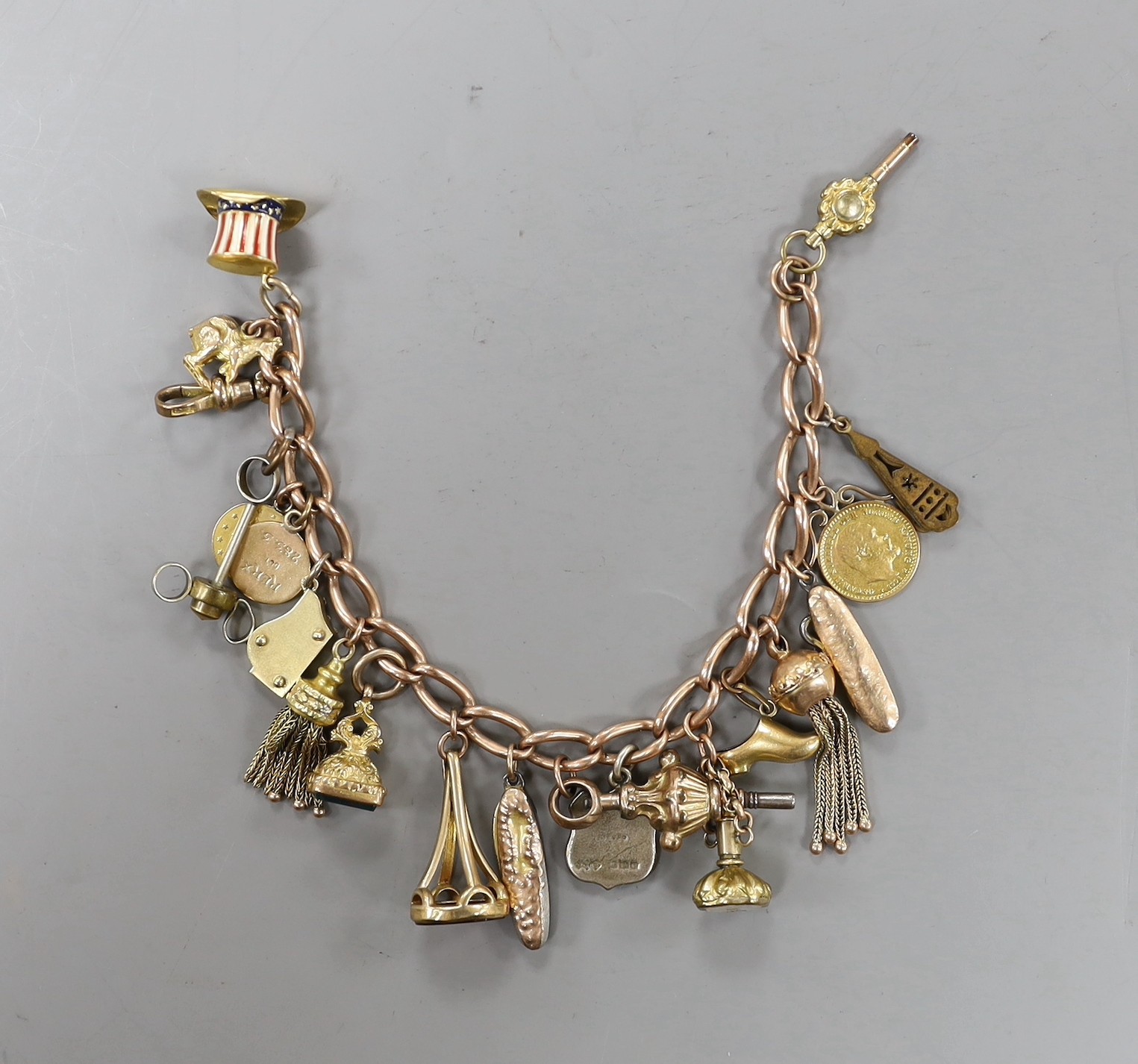 A 9ct charm bracelet, hung with assorted charms including two 9ct, silver and enamel, gilt metal and two gold coins gross weight 61.4 grams.                                                                                