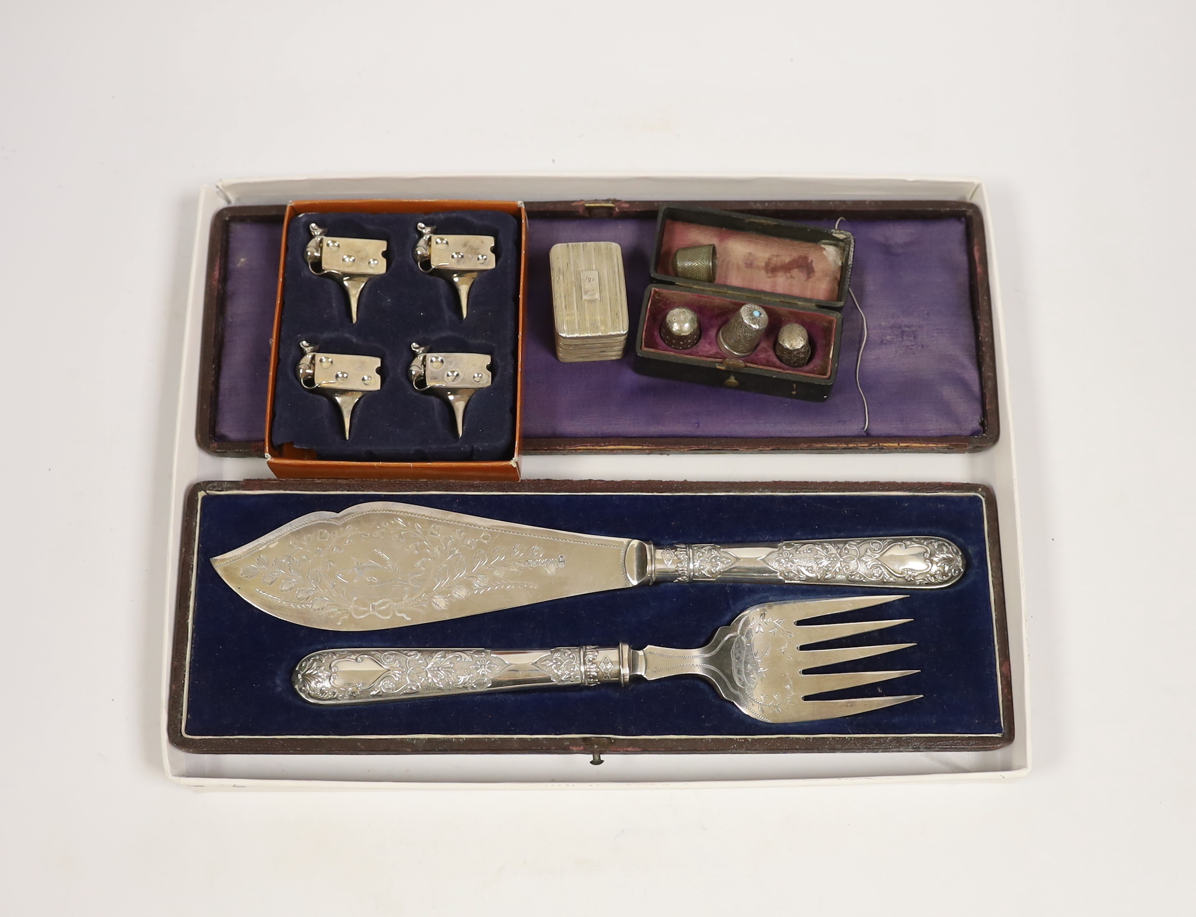 A George III silver nutmeg grater(lacking rasp), Birmingham, 1816, 42mm, together with four assorted thimbles, two silver, a based pair of silver plated fish servers and a set of four metal cheese card holders.          