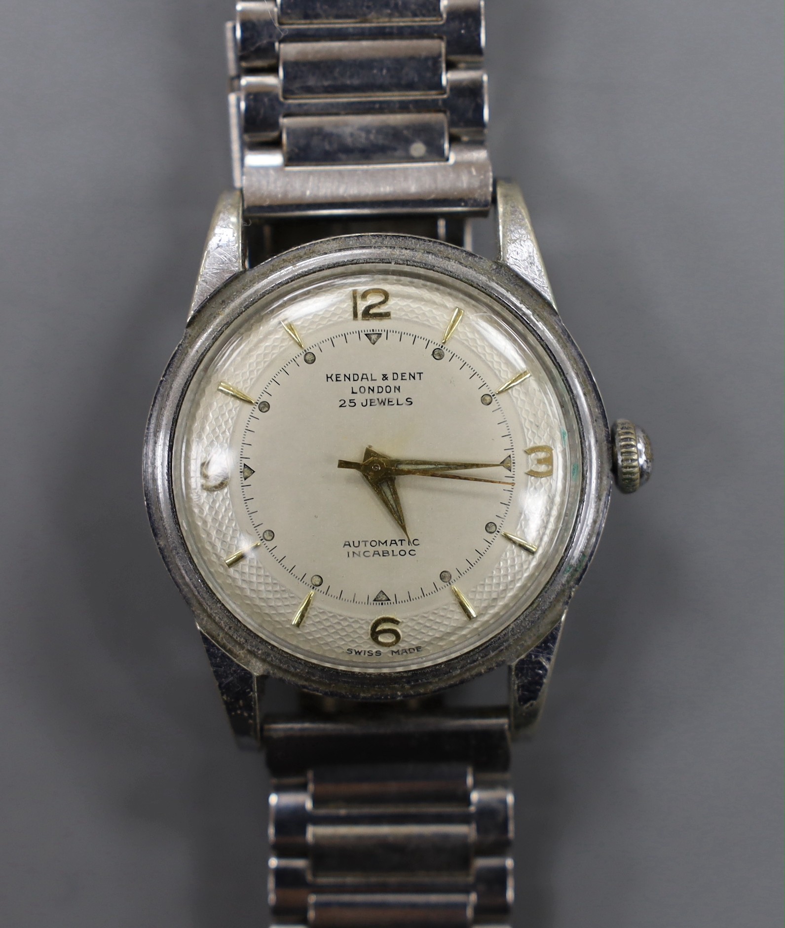 A gentleman's stainless steel backed Kendall and Dent Automatic Incabloc wrist watch, on associated steel bracelet.                                                                                                         