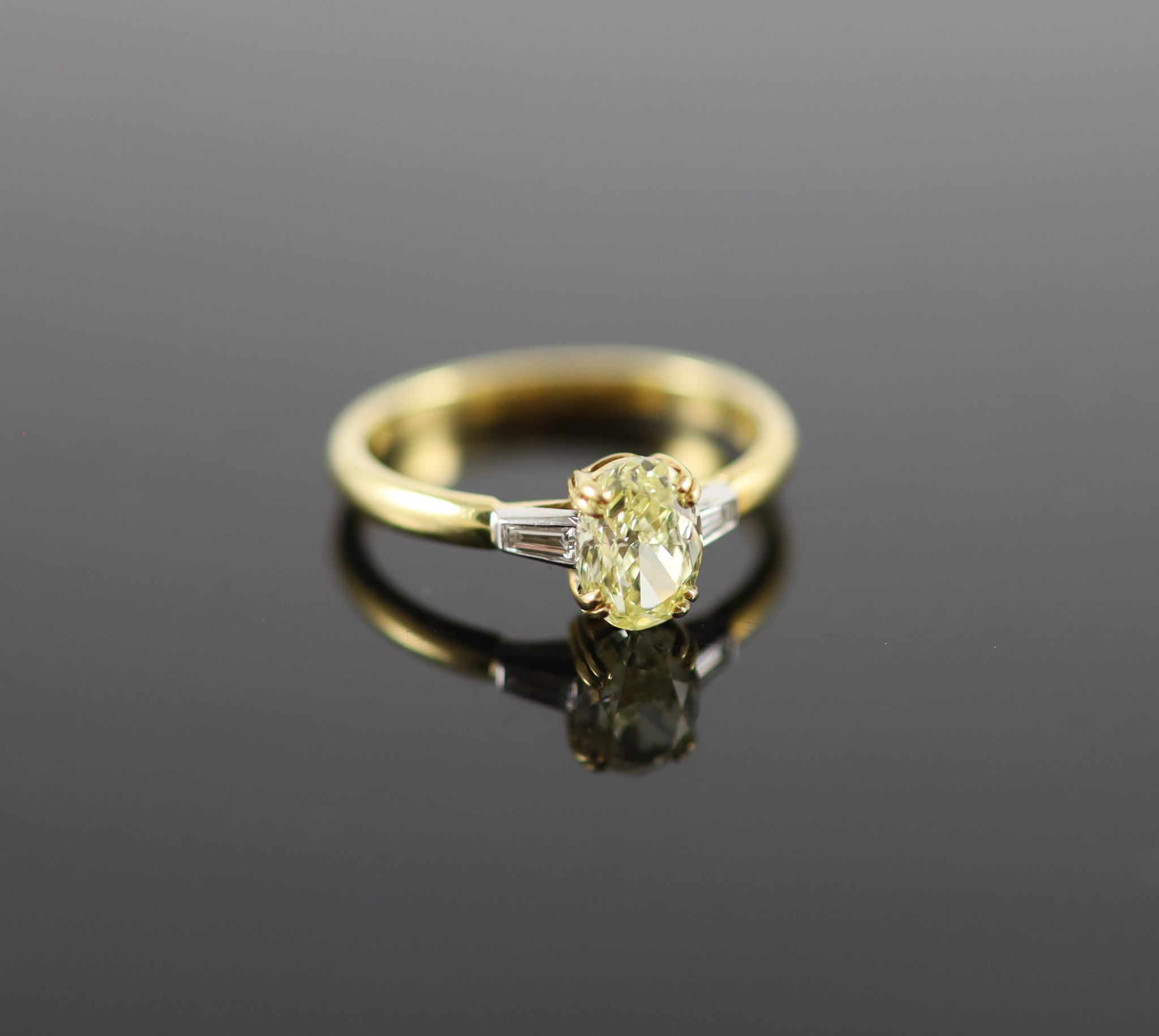 A modern 18ct gold and single stone oval fancy yellow diamond ring, with trapeze cut diamond set shoulders                                                                                                                  