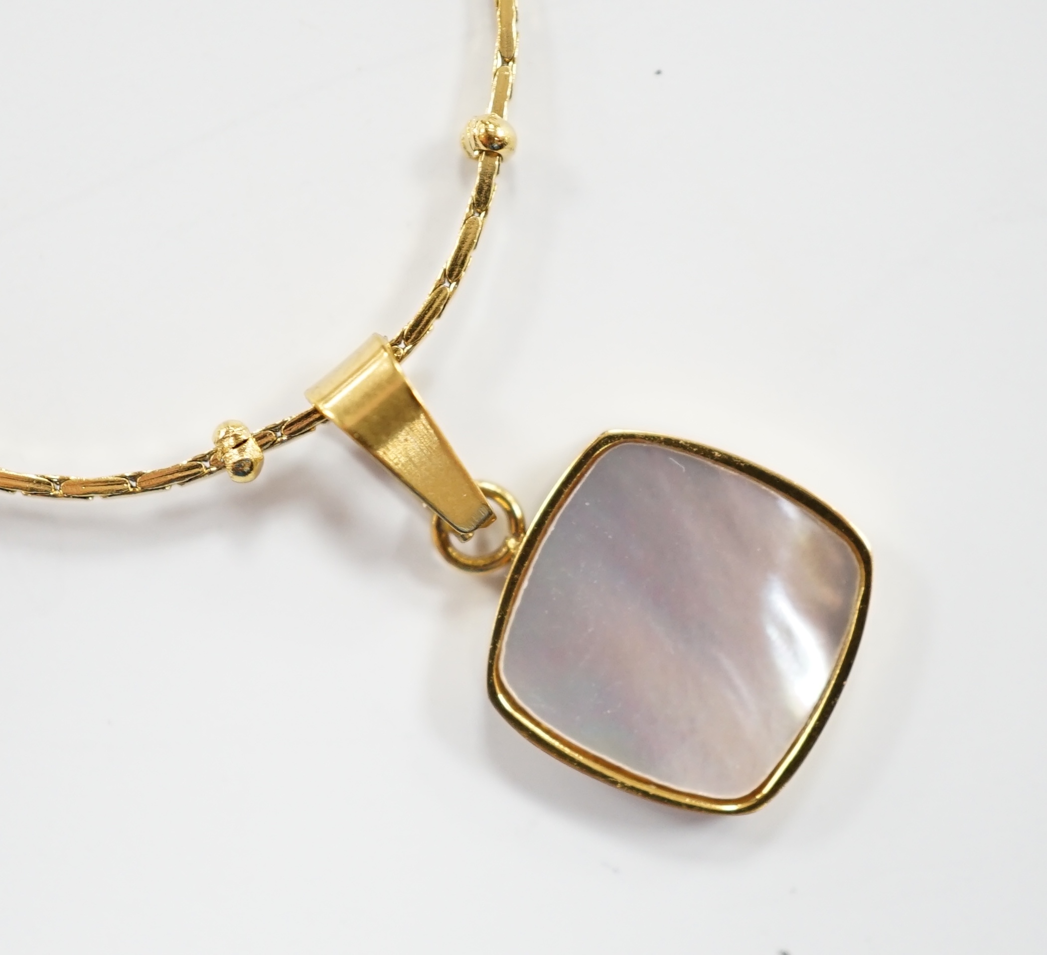 A yellow metal and mother of pearl inset pendant, 11mm on a 18kt fine link chain, 42cm, gross weight 3.4 grams.                                                                                                             