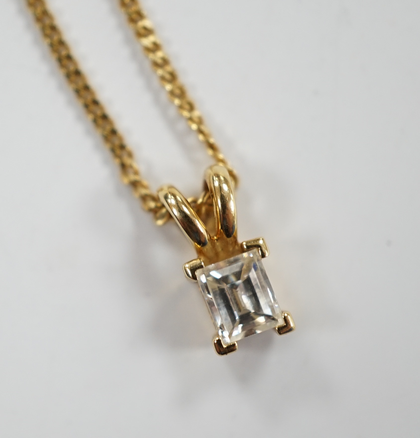 A modern 18ct gold and single stone fancy rectangular cut diamond set pendant, 9mm, on an 18ct gold fine link chain, 46cm, gross weight 3.6 grams.                                                                          