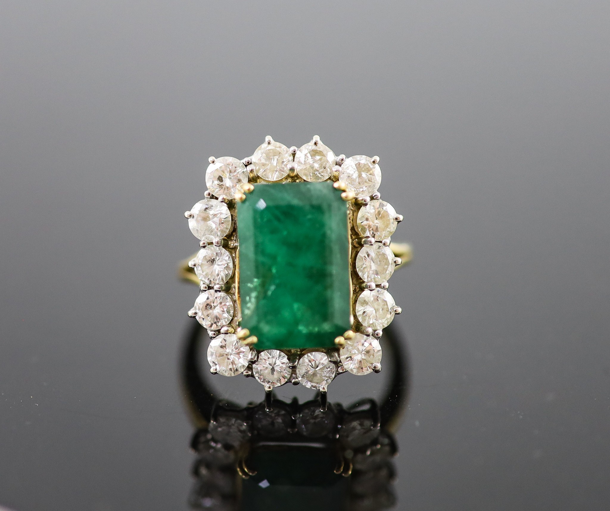 A mid to late 20th century 18ct gold, emerald and diamond set shaped rectangular cluster ring                                                                                                                               