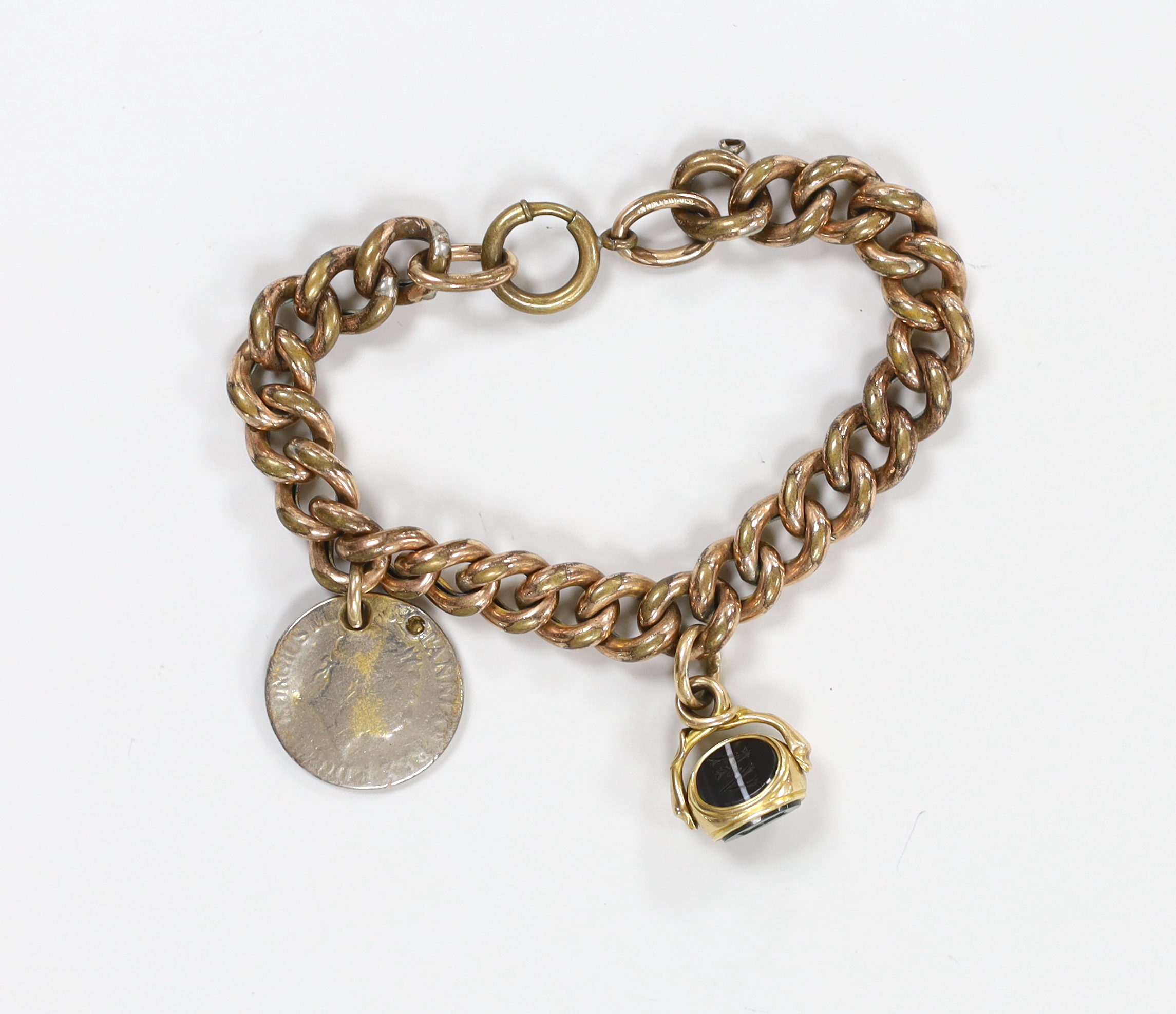 A Victorian gilt metal curb link bracelet, hung with a yellow metal and chalcedony set spinning fob and a worn coin.                                                                                                        