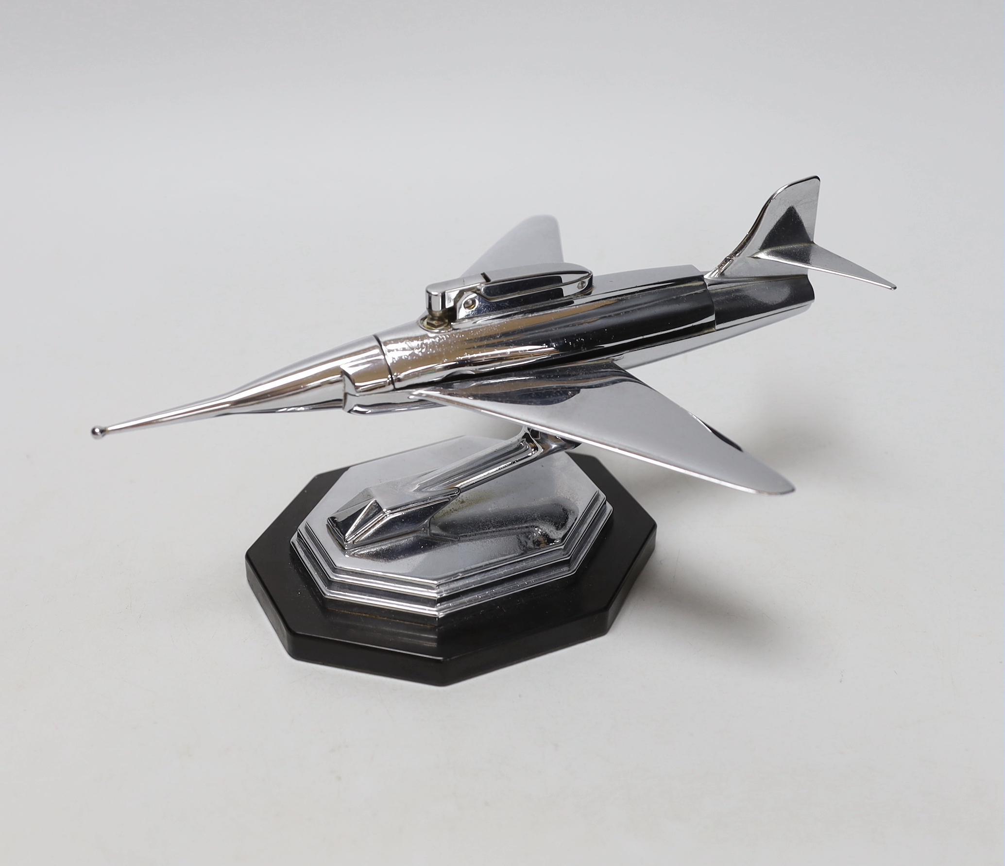 A chrome novelty table lighter in the form of a jet aircraft raised on an octagonal base, 24cm wide                                                                                                                         