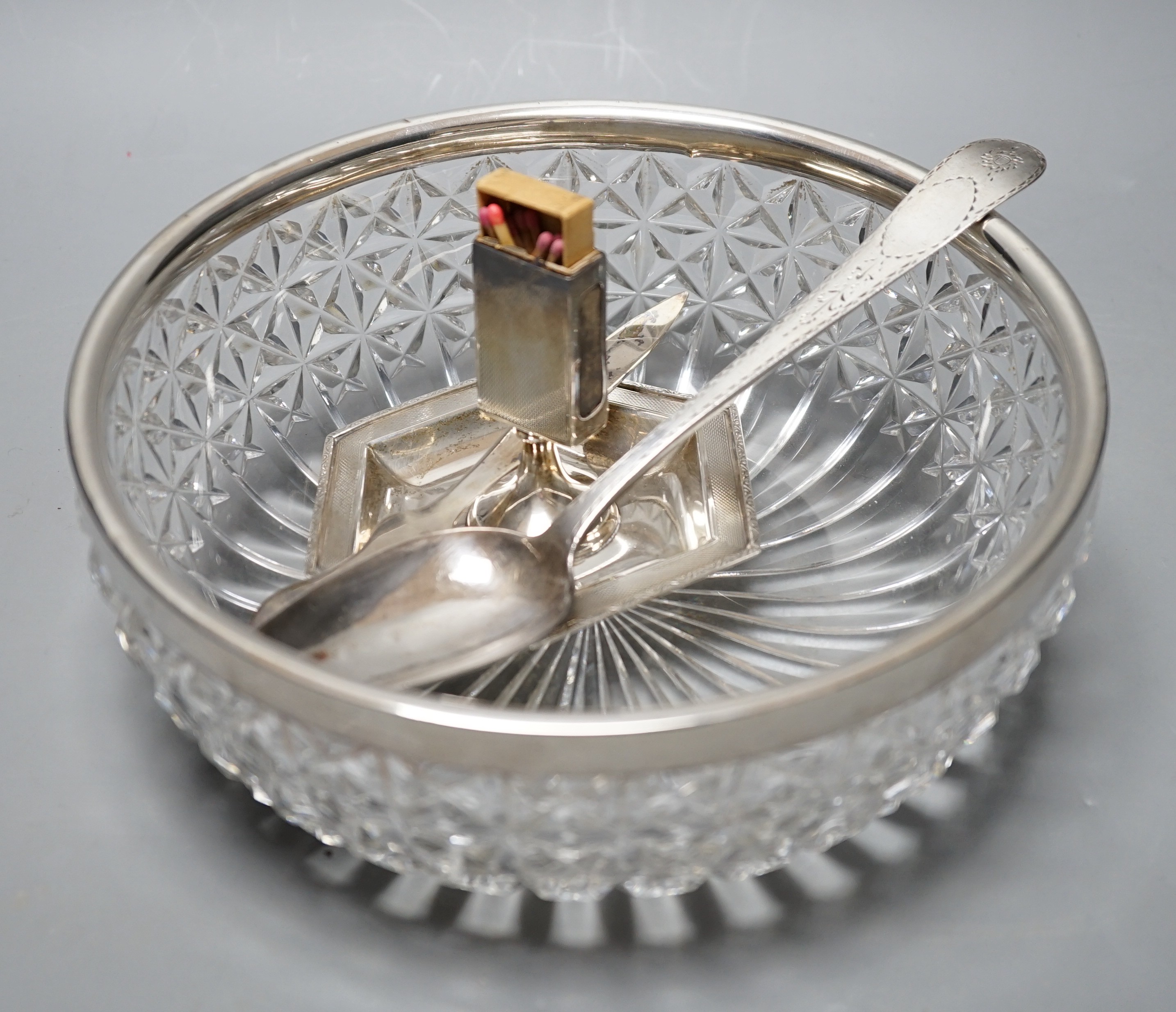 A George III Irish bright cut engraved silver tablespoon, Dublin, 1798, a silver match sleeve/ashtray, a silver rimmed fruit bowl fruit bowl and 925 letter opener.                                                         