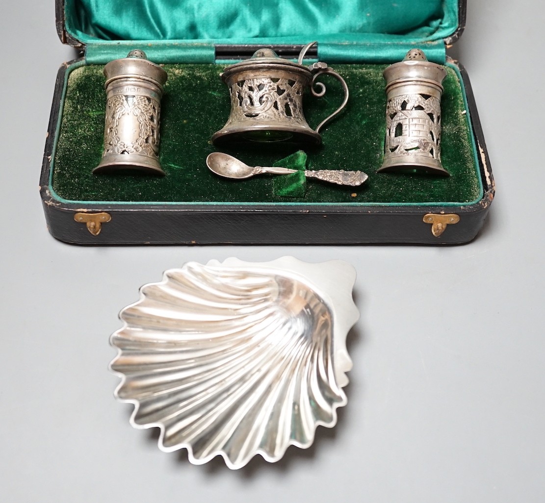 A late Victorian silver butter shell, London, 1892, 11.5cm and a cased George V silver three piece condiment set with green glass liners.                                                                                   