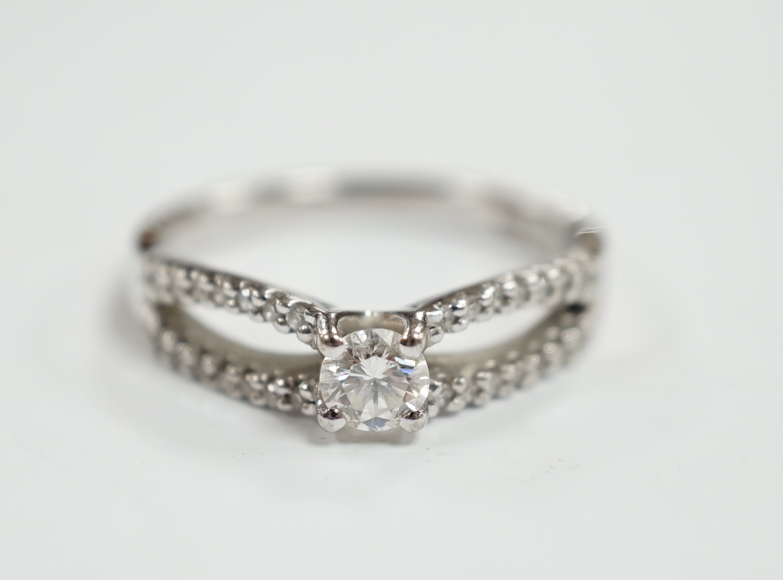 A modern 18ct white gold and single stone diamond set ring, with diamond chip set split shoulders, size O, gross weight 4.2 grams.                                                                                          