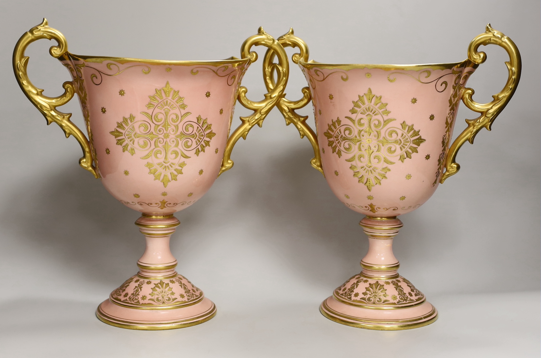 A pair of large Coalport salmon pink ground two handled loving cups, 28.5cm                                                                                                                                                 