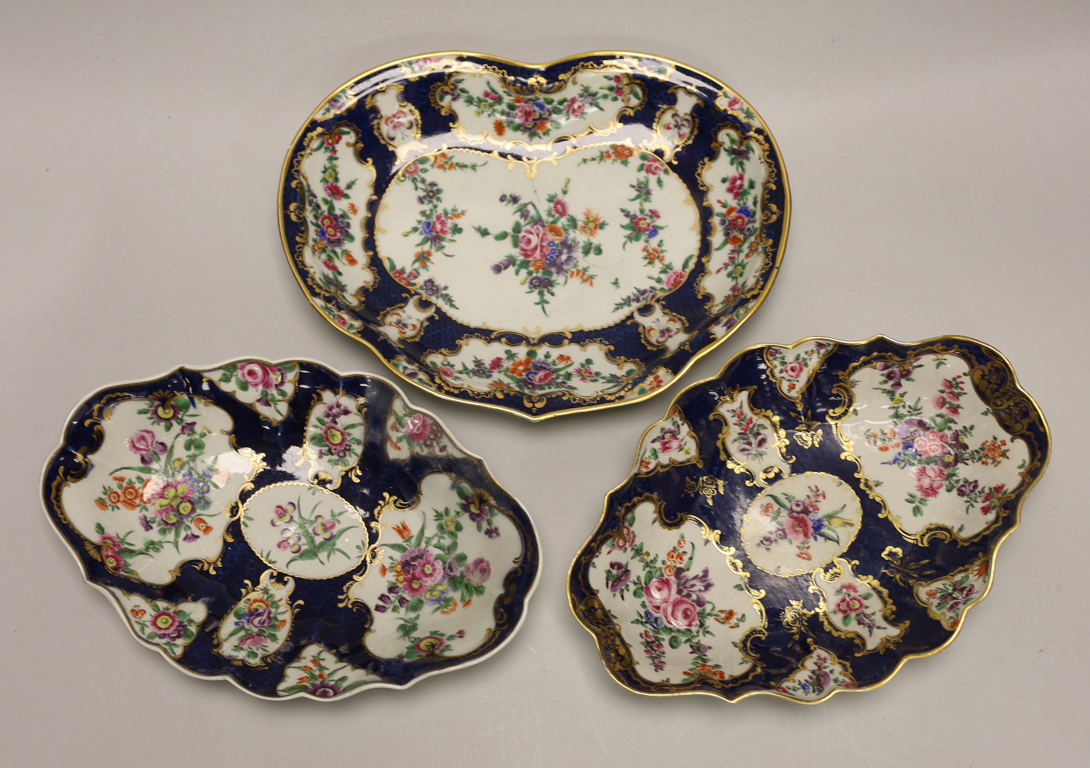 A pair of Worcester oval lobed dishes painted with flowers on a blue scale ground and a matching heart shaped dish-28cm wide x 21cm high                                                                                    