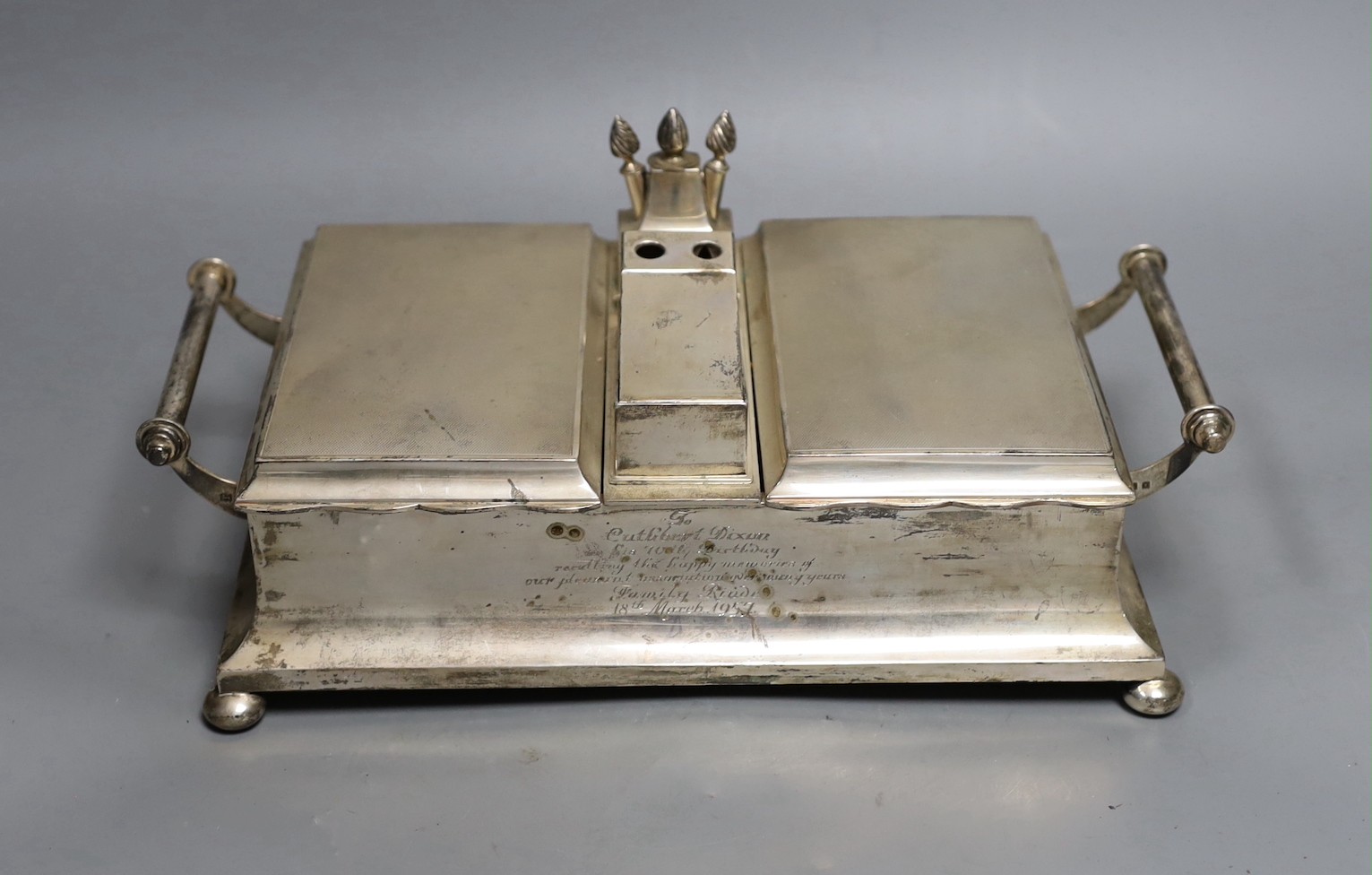 A George V silver mounted two handled desk top twin cigarette box incorporating a cigar cutter and lighters, with 1957 presentation inscription, Mappin & Webb, London, 1926, width 33.5cm.                                 
